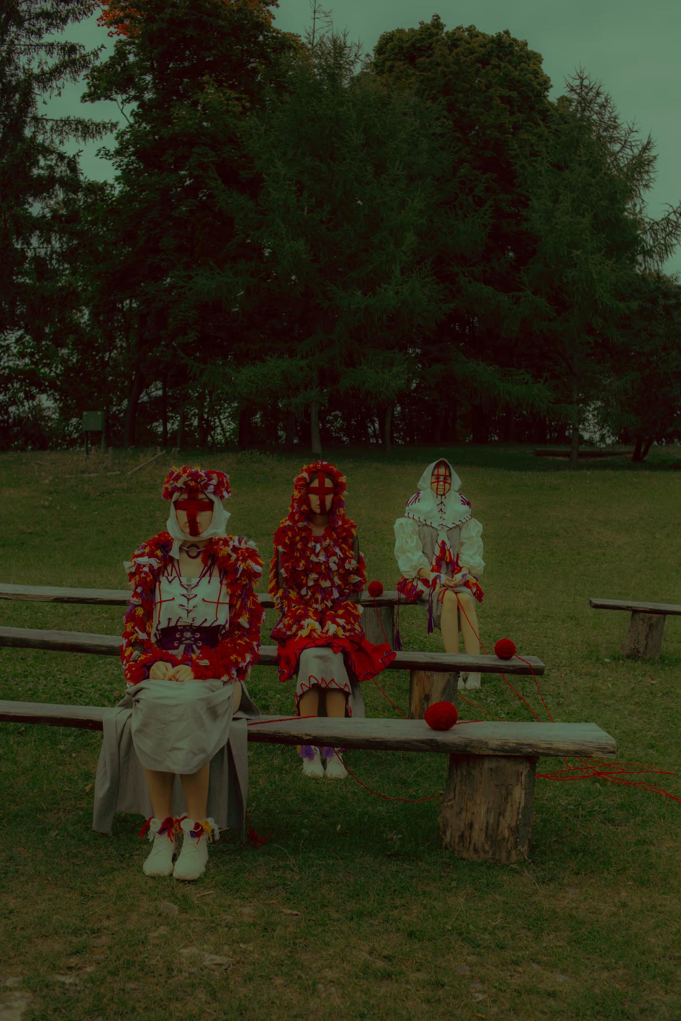 Symmetric fashion shot of models in folk-inspired headpieces seated on a wooden bench, evoking a sense of Ukrainian cultural storytelling.