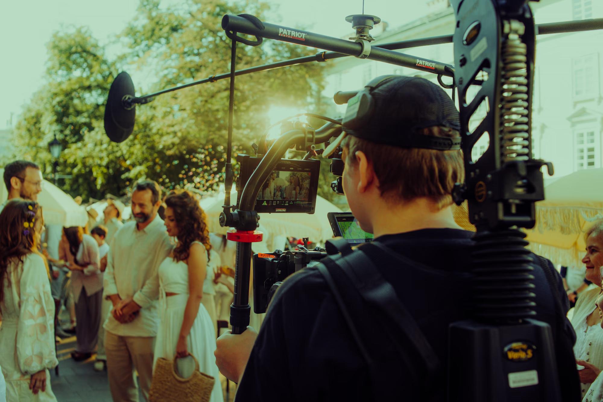 Outdoor film set in a Lviv street, showing the boom operator and camera crew filming a crowded scene.