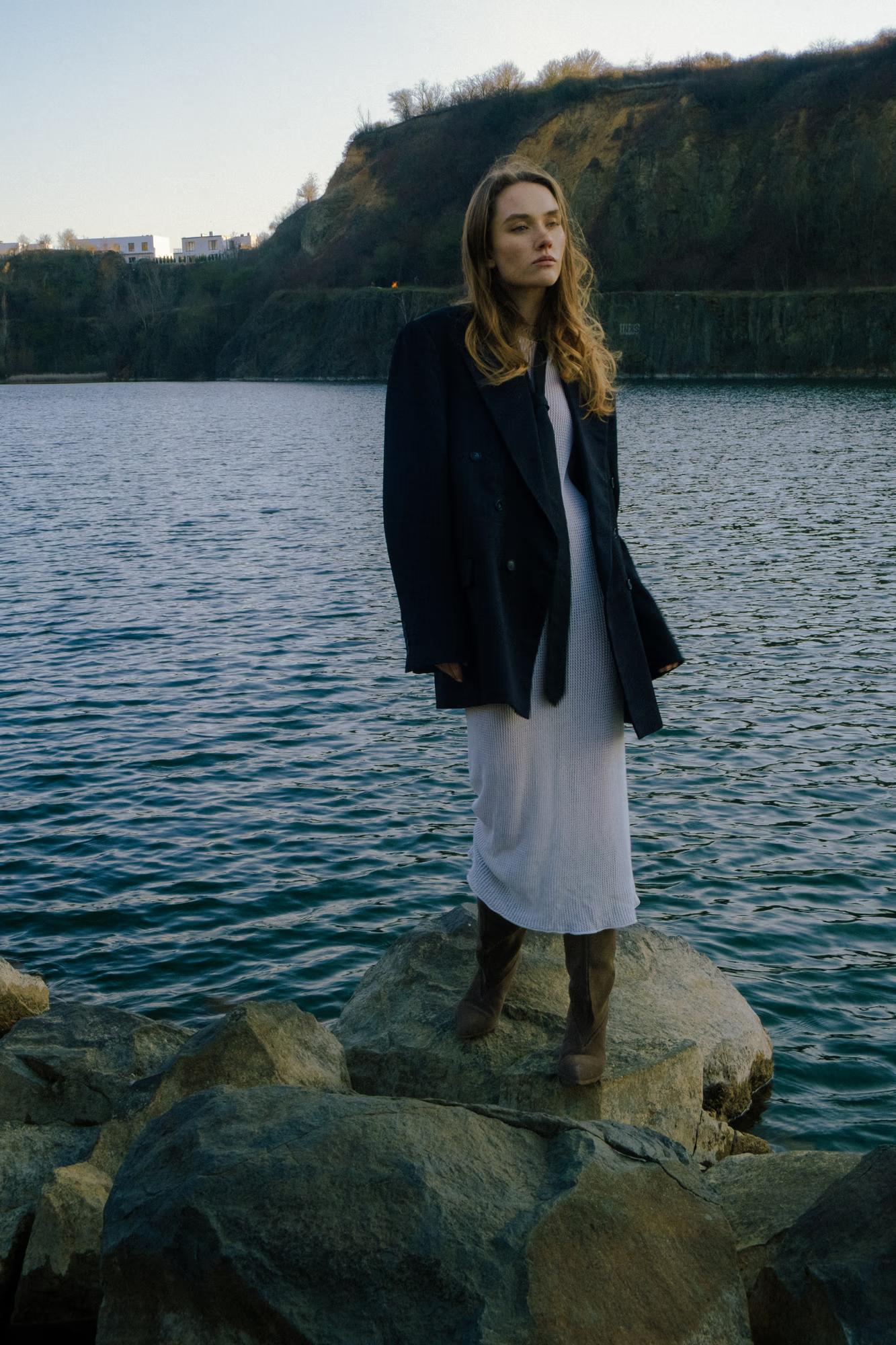 Vertical portrait: Close-up of the model's face looking over her shoulder, lake background, cinematic lighting.
