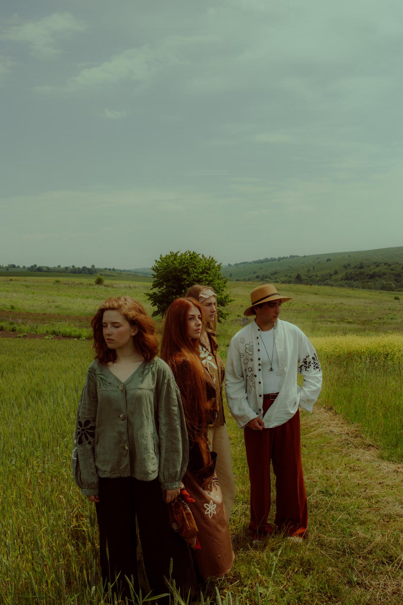 Full body fashion campaign wide shot of group of women in Ukrainian designer ethnic outfits in green poppy field, soft natural light, Ukraine countryside