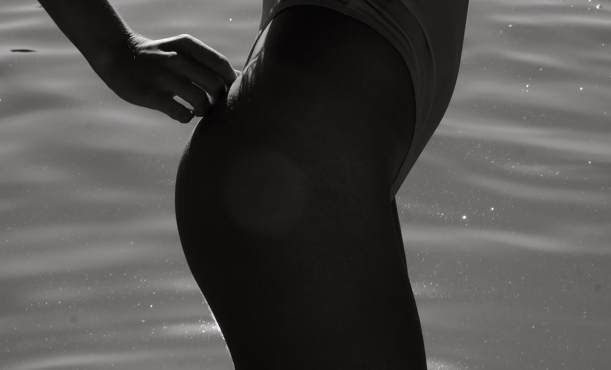 Black and white underwater silhouette of woman submerged in lake, dramatic contrast, artistic fine art nude photography
