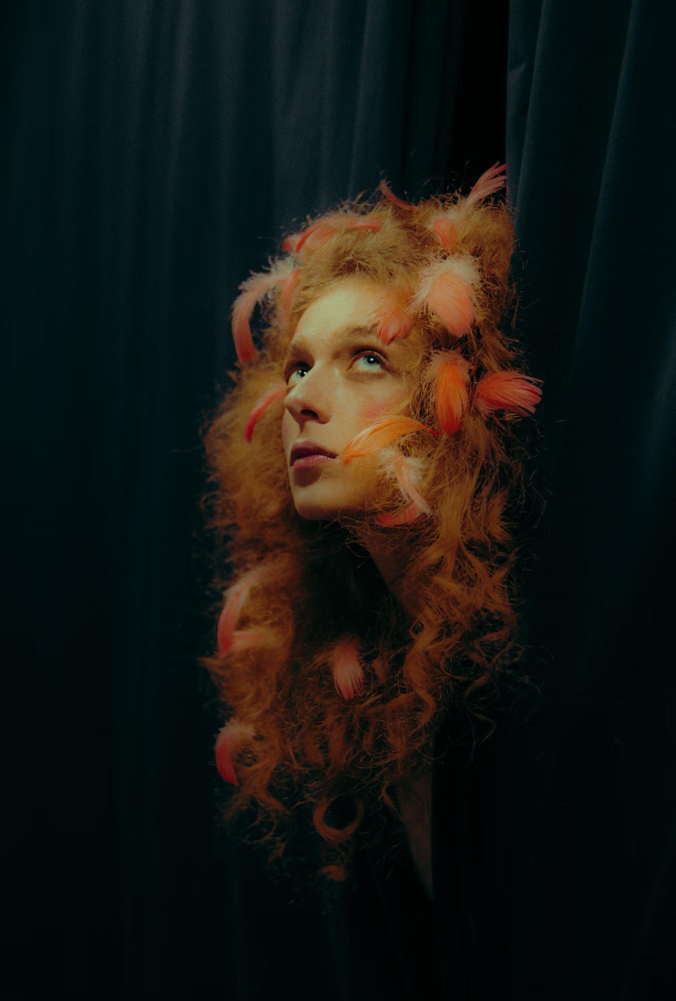 Mysterious portrait of a redhead woman framed by theatrical curtains, dramatic shadows.