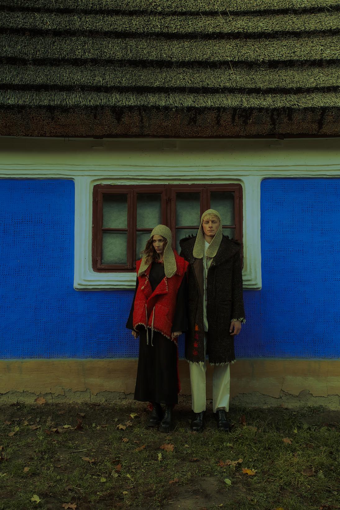 Models posing in front of a traditional blue-walled Ukrainian cottage (hata) in Pirogovo, blending Scandi-minimalism with folk heritage.