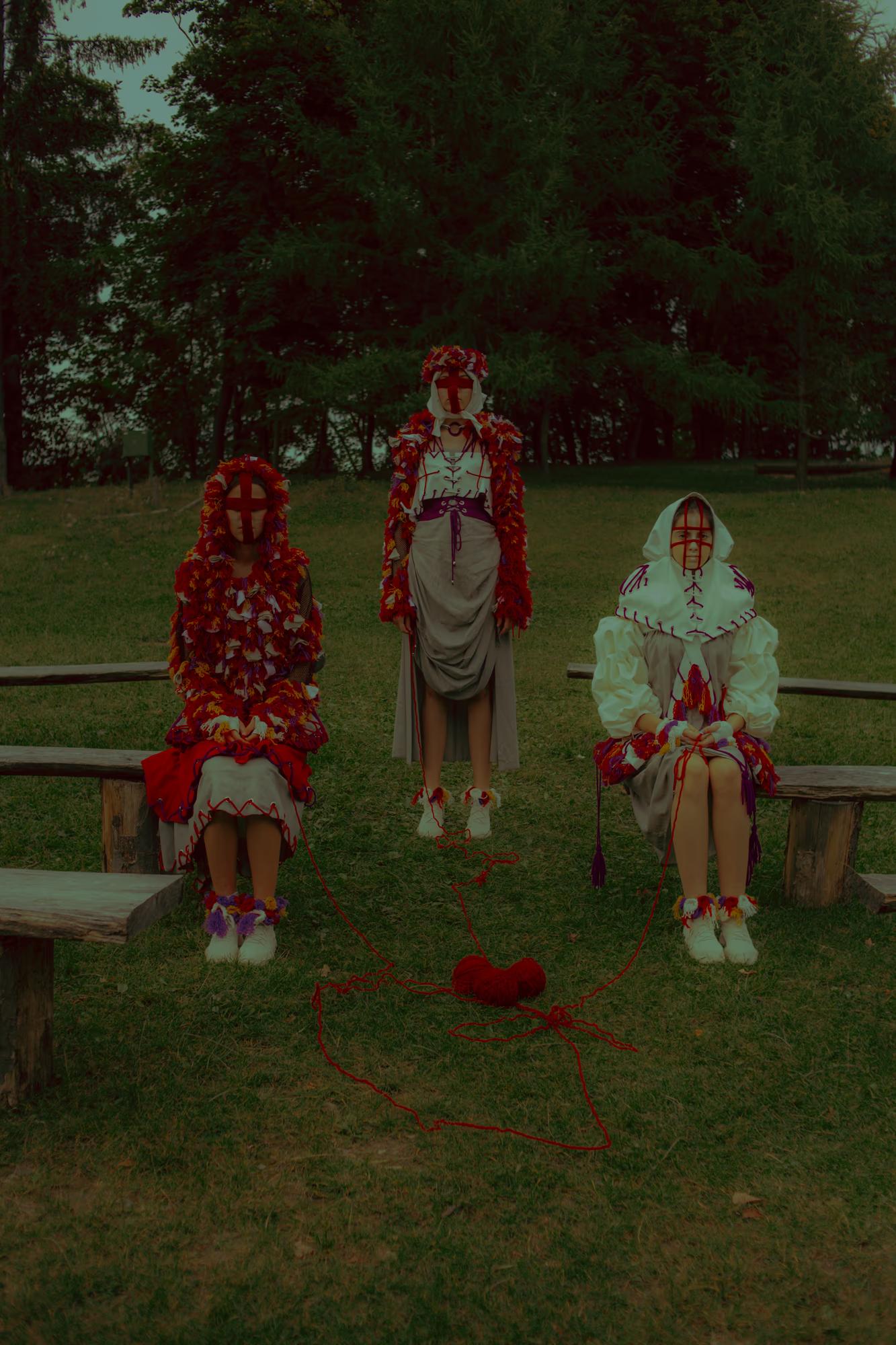 Fashion campaign shot featuring models in traditional floral wreaths and embroidered garments standing on a lush green lawn in Shevchenkivskyi Hai.
