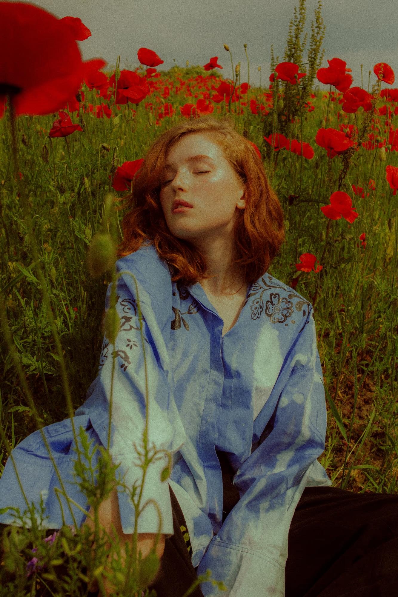 Full body fashion campaign shot of woman in blue Ukrainian designer outfit standing among red poppies in bloom, vibrant color contrast, Ukraine field editorial