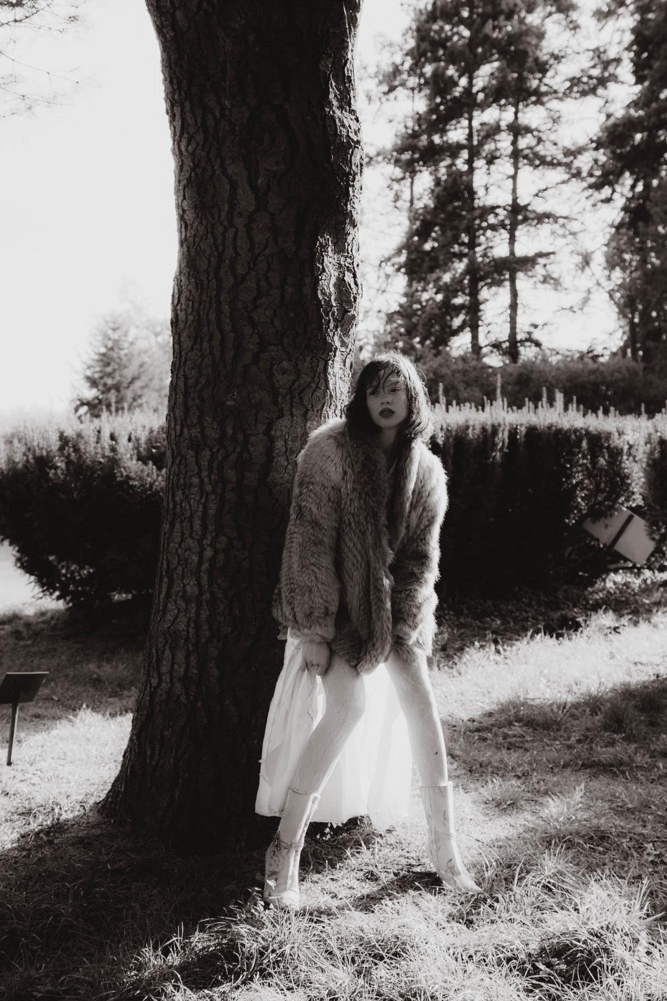 Full body black and white fashion art shot of woman in dramatic outfit in dark forest with waterfall, fine art dark fantasy editorial