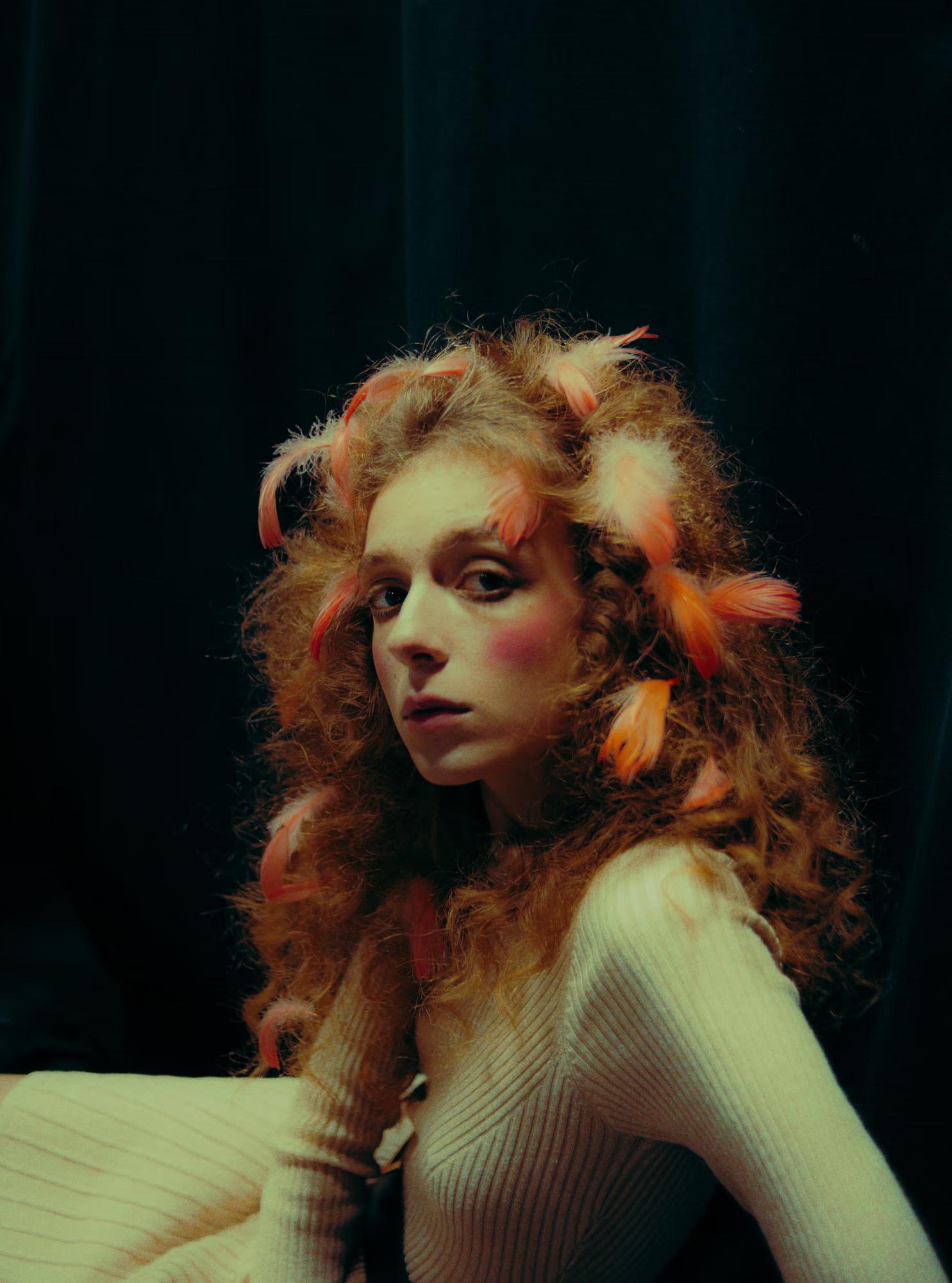Redhead model in white dress posing against dark green theater curtains, art fashion photography.