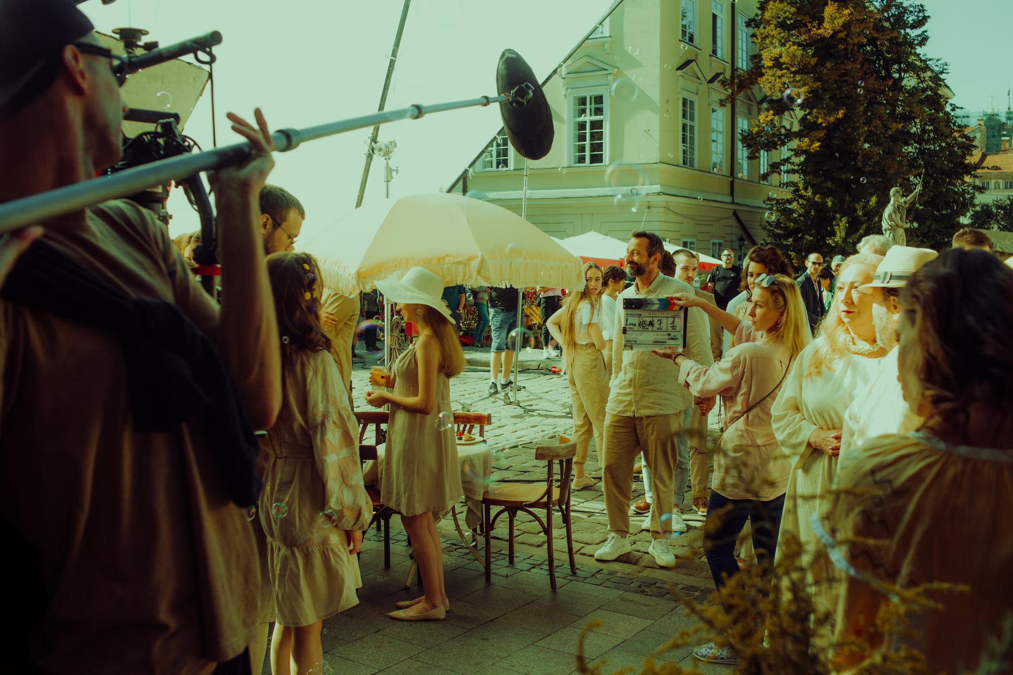 Wide view of a street film production, featuring vintage cars and extras in authentic historical costumes.