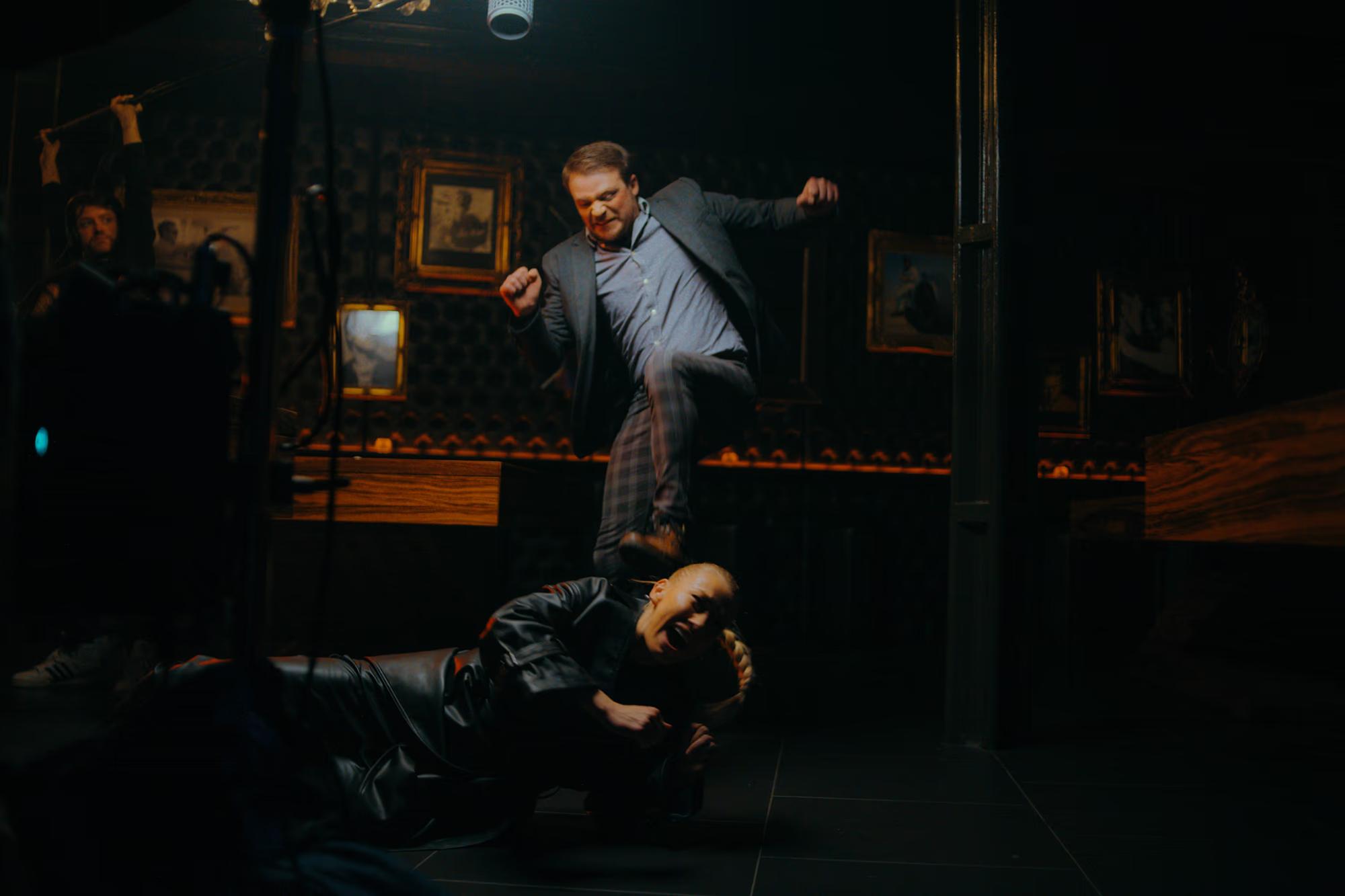 Action movie set: Stunt performers rehearsing a high-intensity fight scene on a bar counter.
