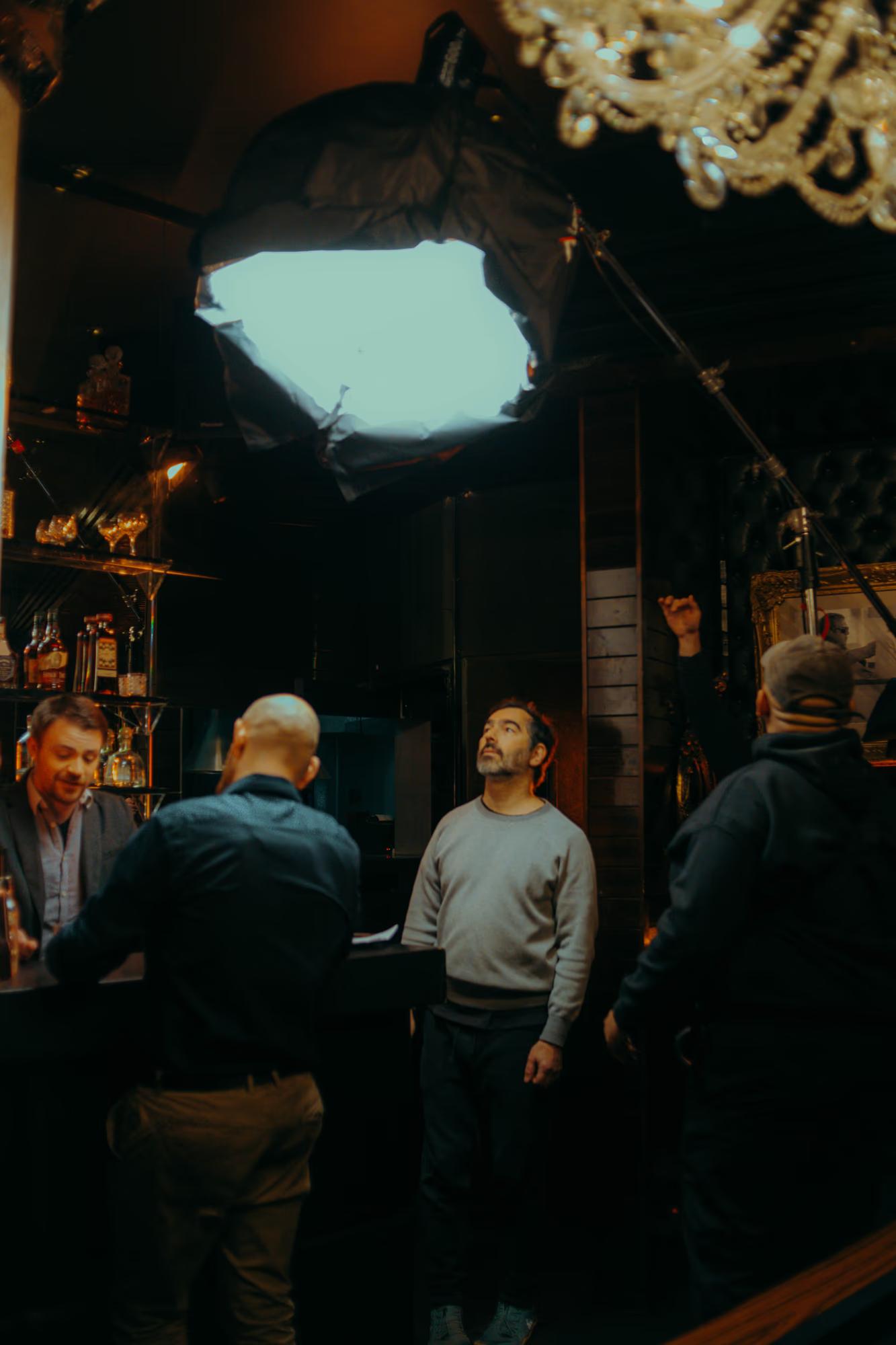 Production team gathered under a large softbox light, discussing the technical details of the next take.