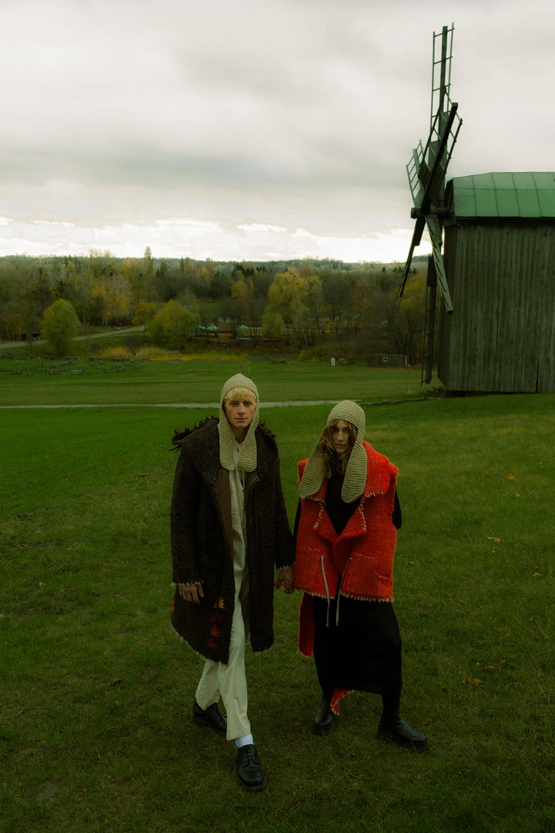 Wide-angle view of models exploring the historic village of Pirogovo, featuring iconic windmills and traditional huts.