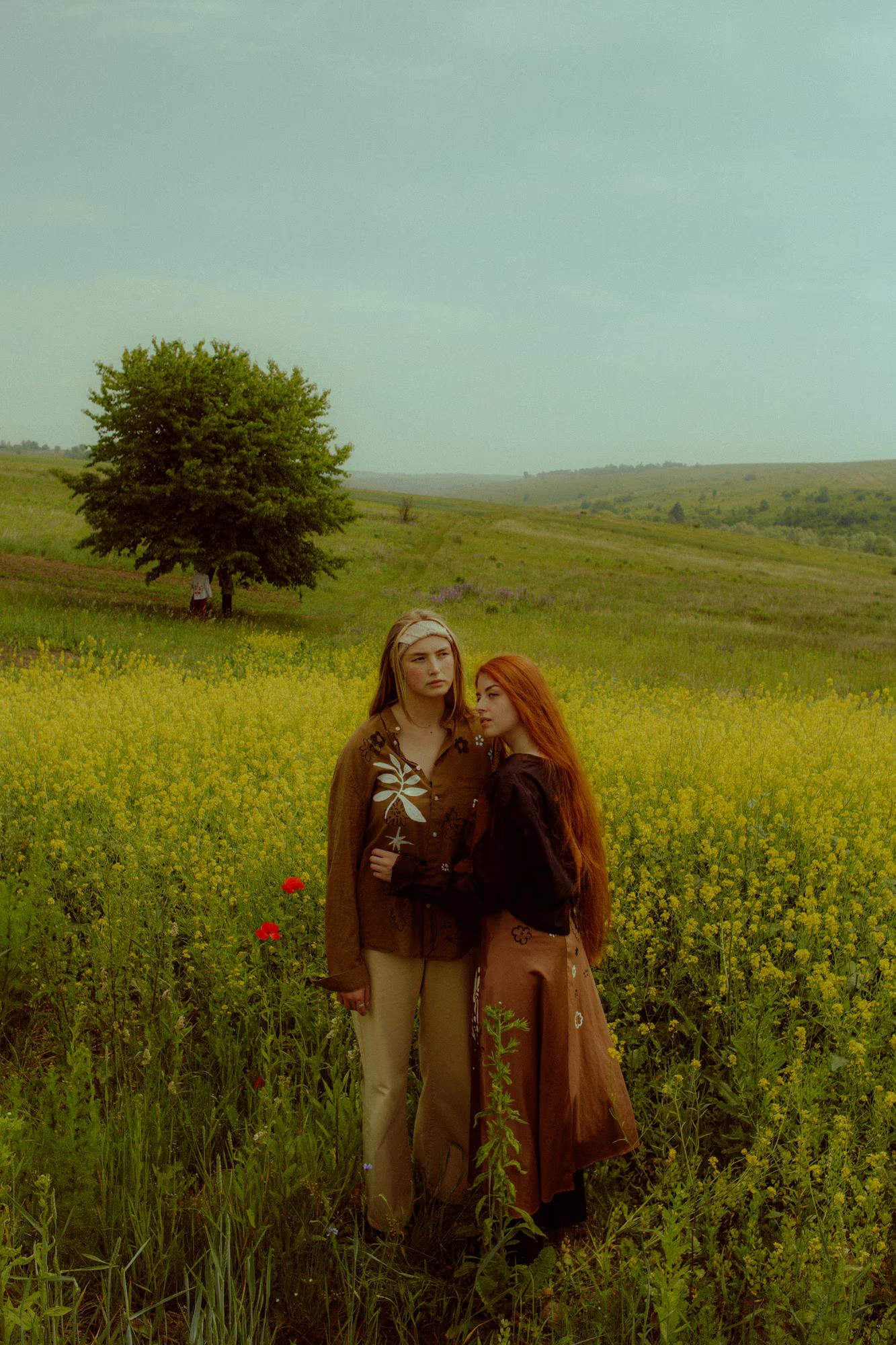 Full body fashion campaign shot of woman in designer ethnic outfit standing in green poppy field, Ukraine countryside, soft overcast light