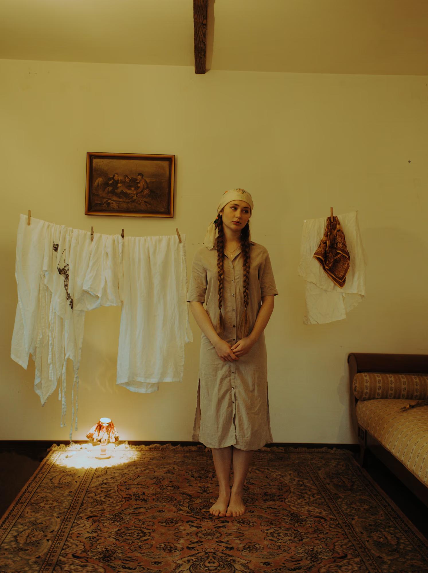 Full body fashion art shot of woman in white traditional dress standing in aged interior room, soft ambient light, ethereal ethno art editorial