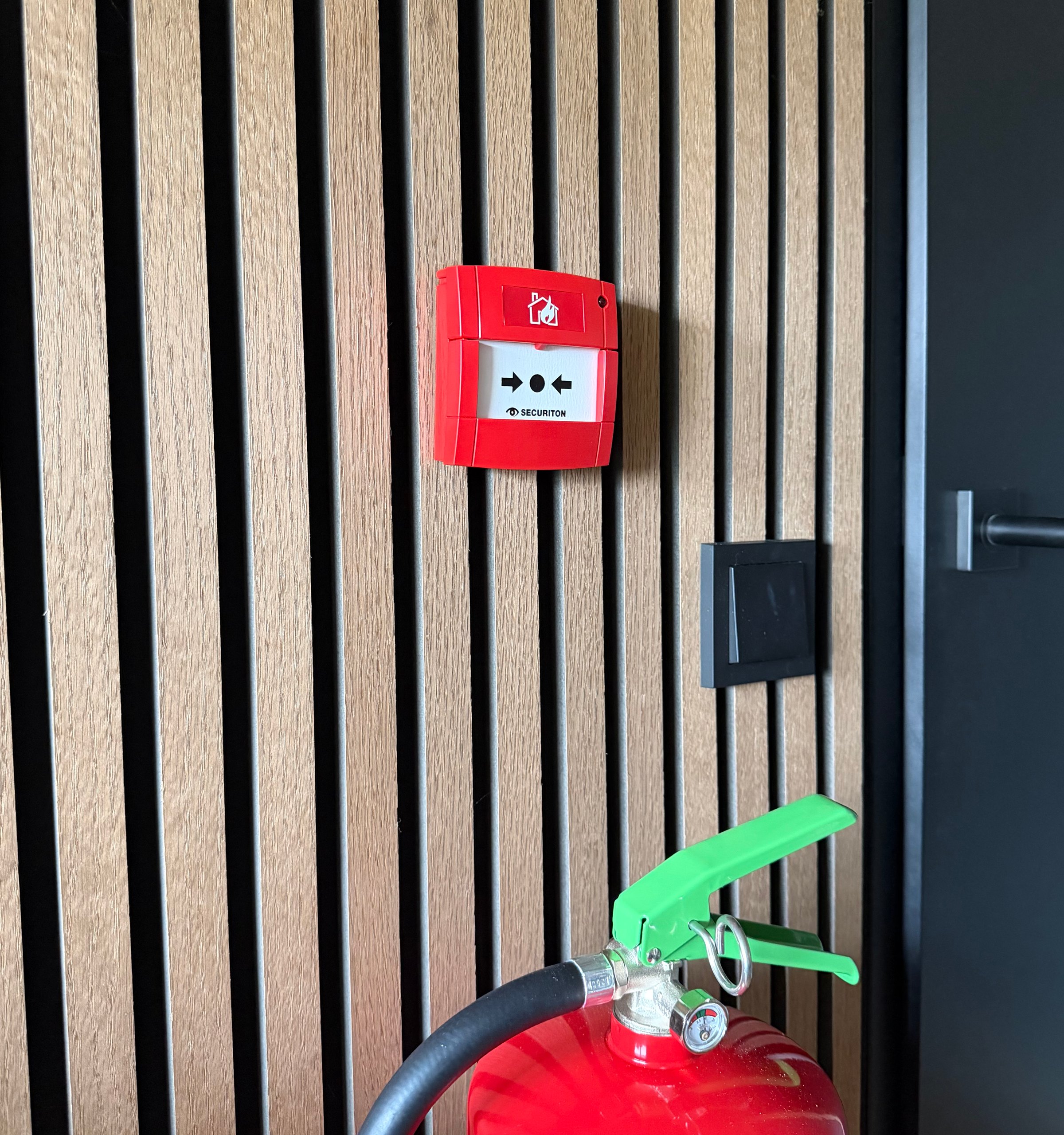 handbrandmelder op muur met brandblusser