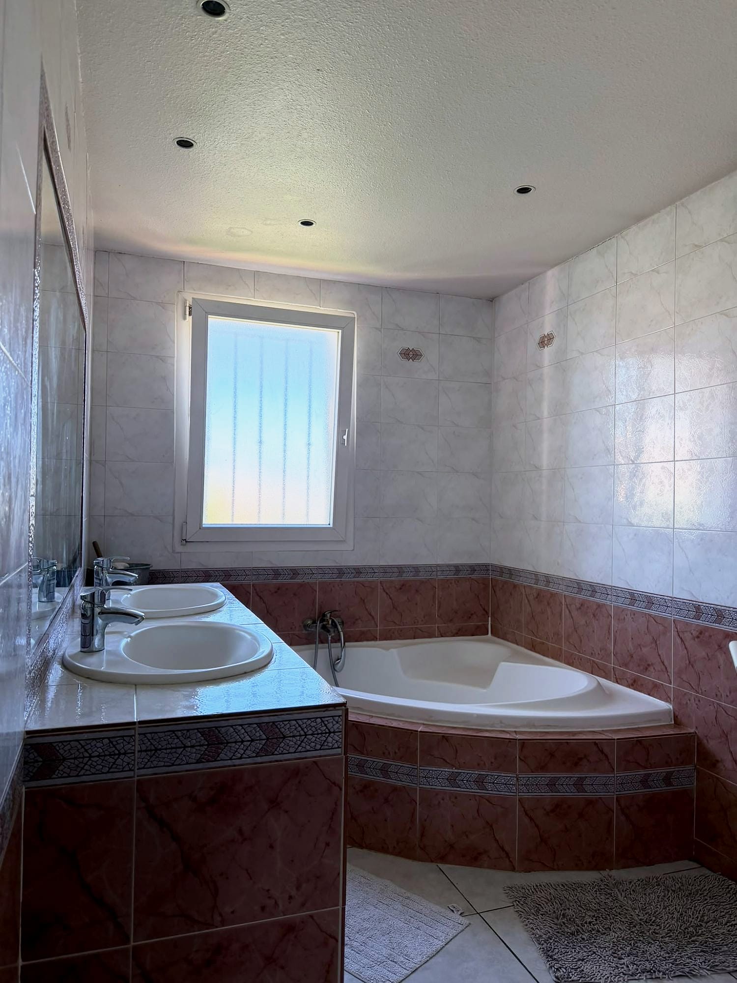 Salle de bains avec baignoire d’angle et double vasque