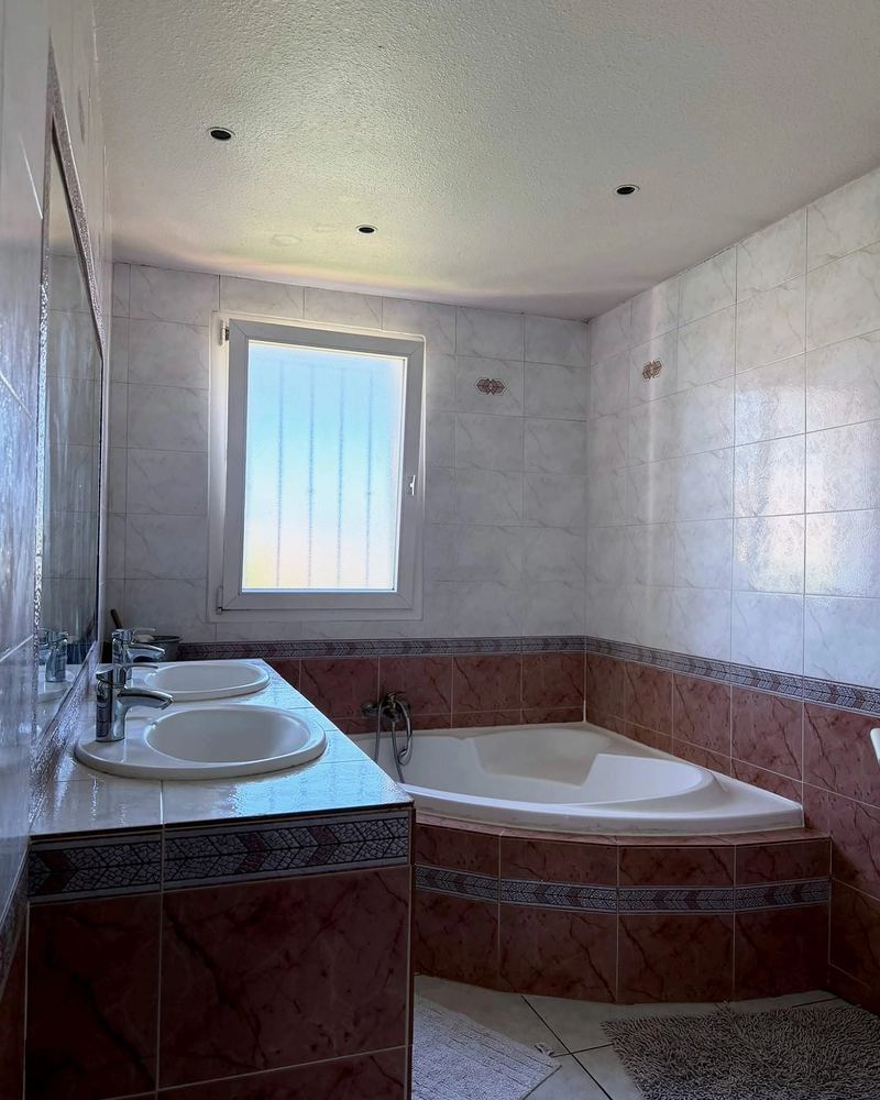 Salle de bains avec baignoire d’angle et double vasque