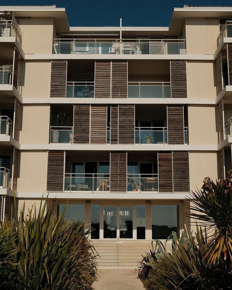 Façade de la résidence et son jardin planté de palmiers