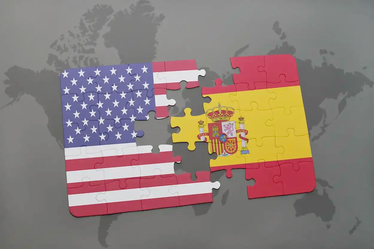 Dos piezas de rompecabezas con las banderas de Estados Unidos y de España encajando sobre un mapamundi.