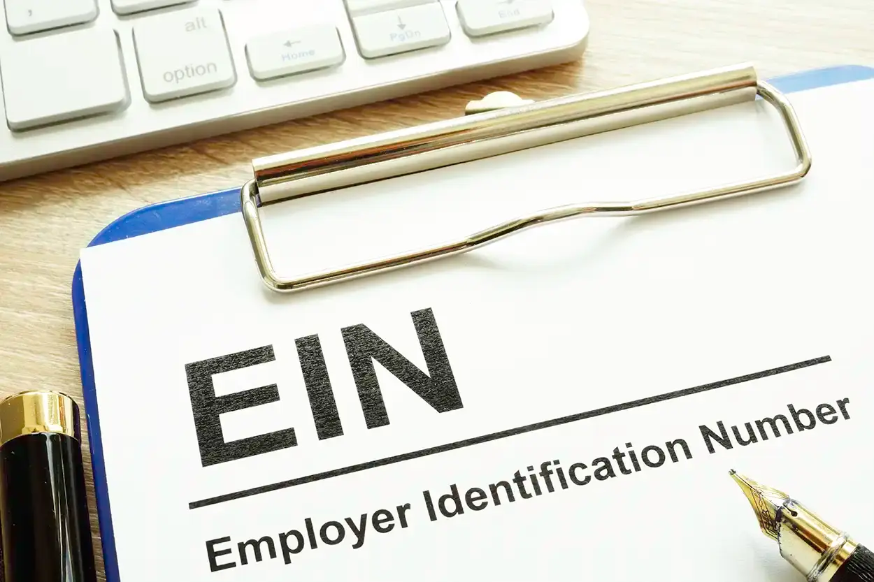 Un portapapeles con un formulario de Employer Identification Number, sobre un escritorio con un bolígrafo y un teclado.