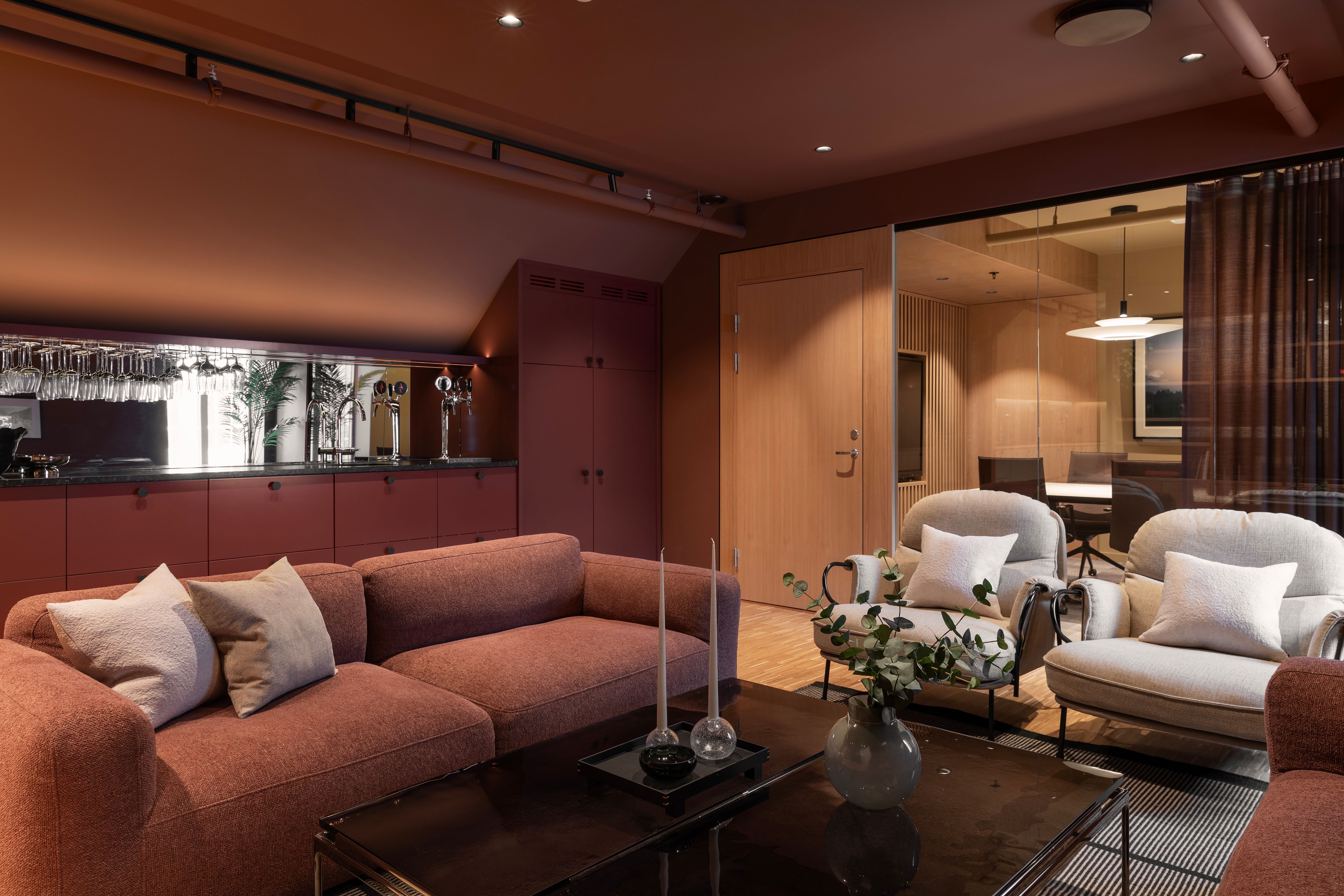 Interiøret i loungen med røde toner i vegg og tekstiler skaper en lun og inviterende sone.