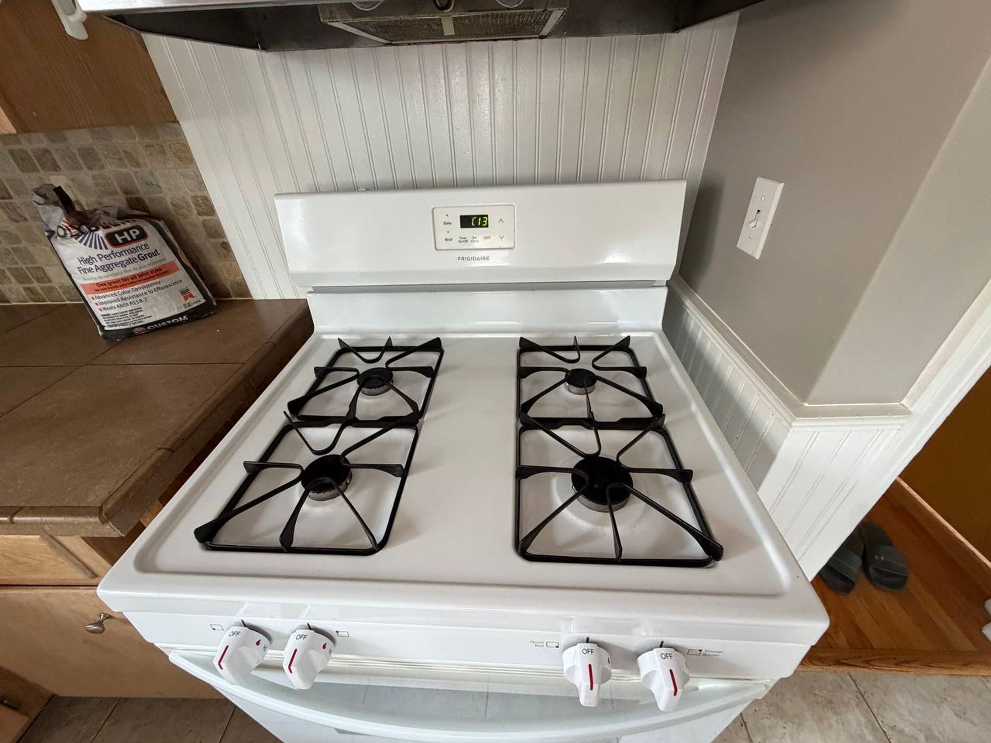 Clean white gas range with black grates beside tile counter