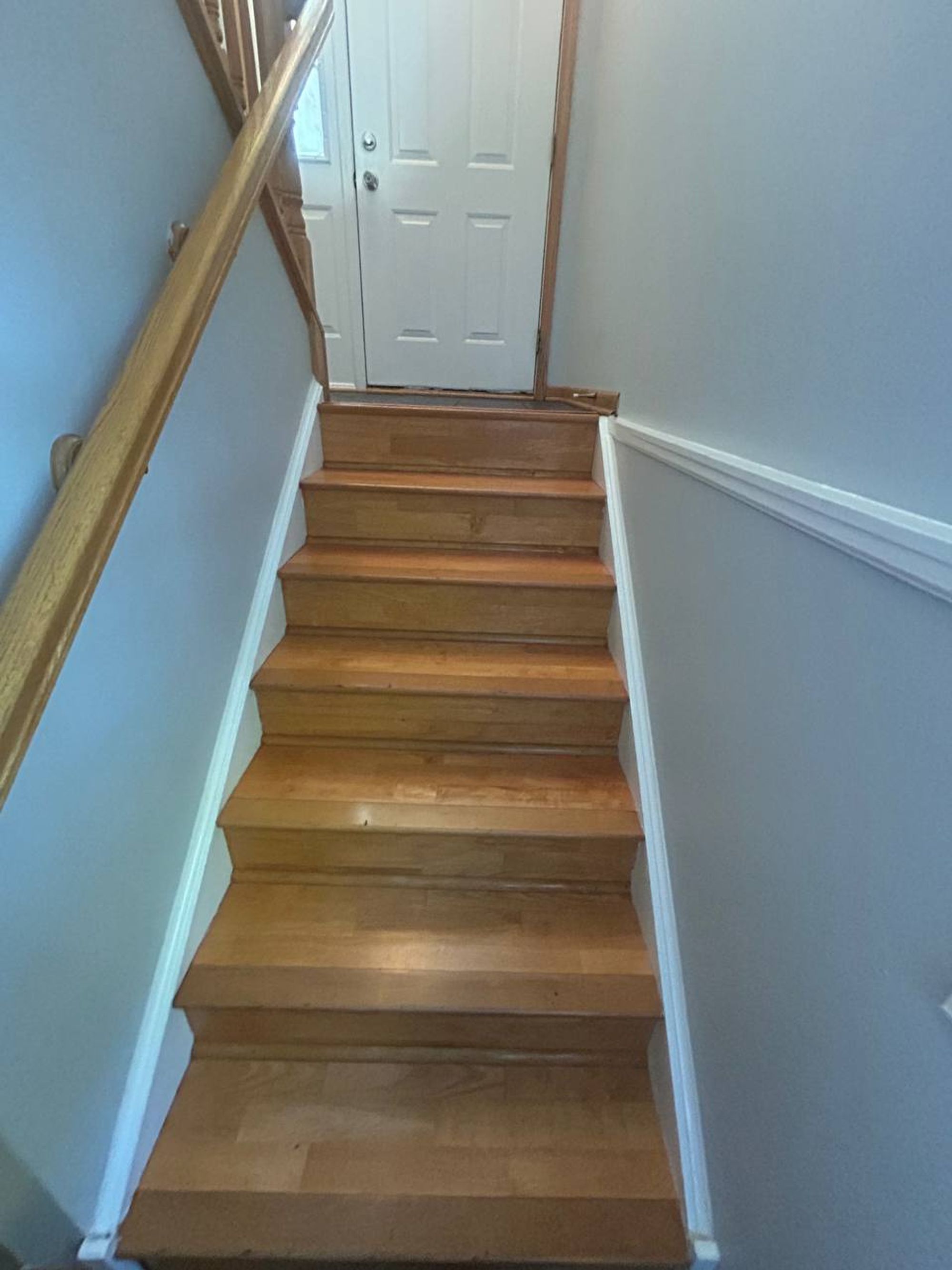 Wood stairs leading up to a white front entry door