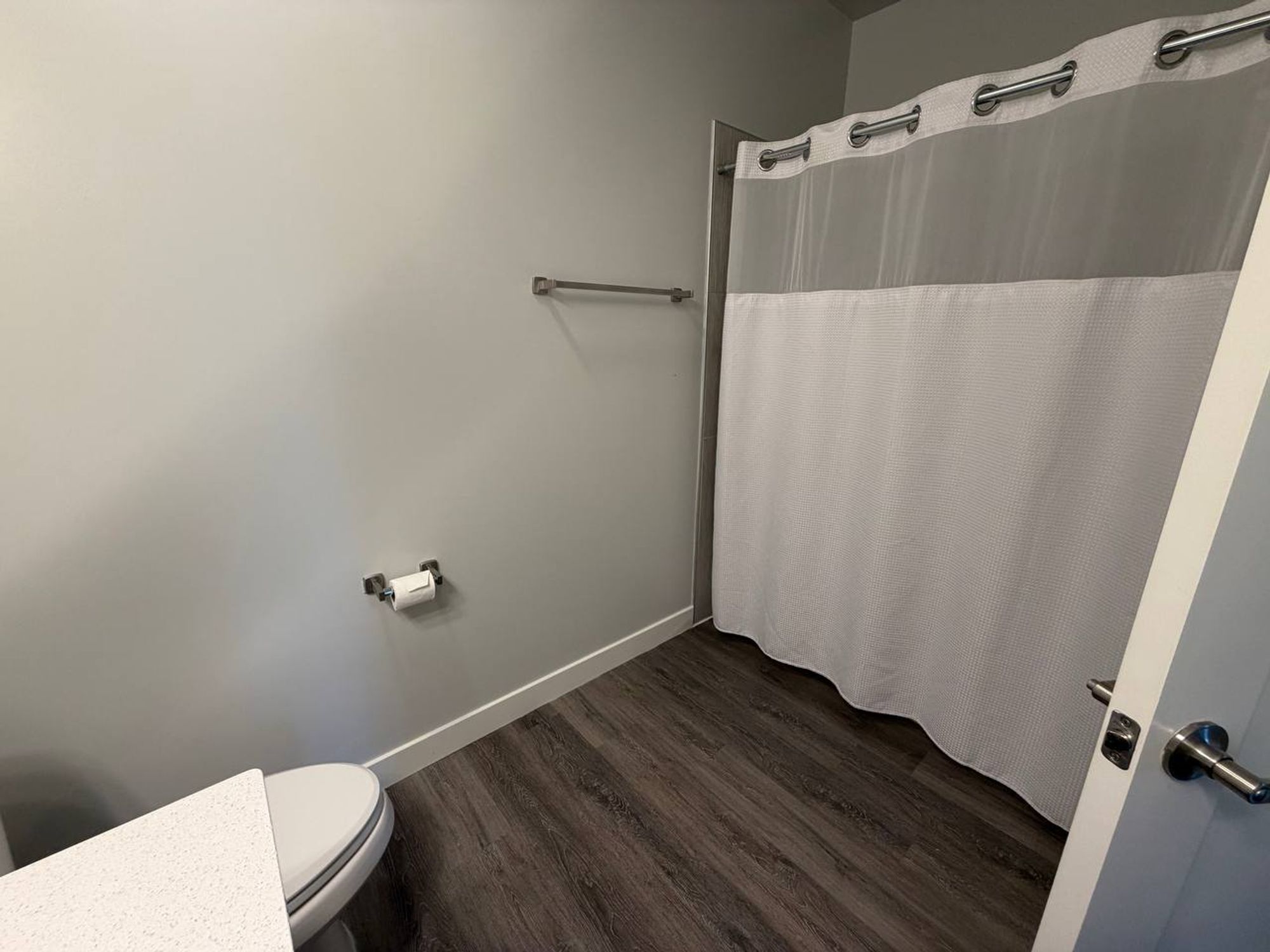 Bathroom with white waffle shower curtain and wood-look floor