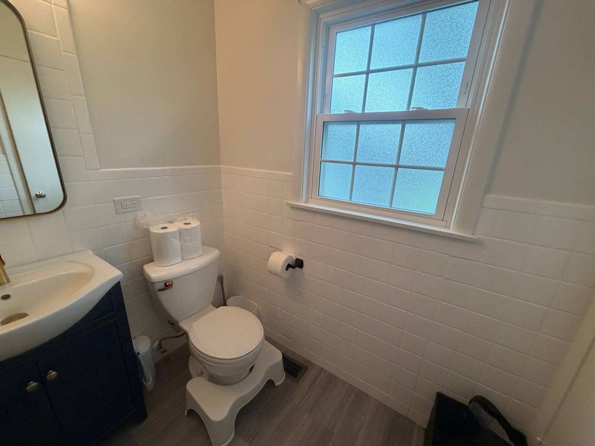 Bathroom with frosted window, white tile walls and gray floor