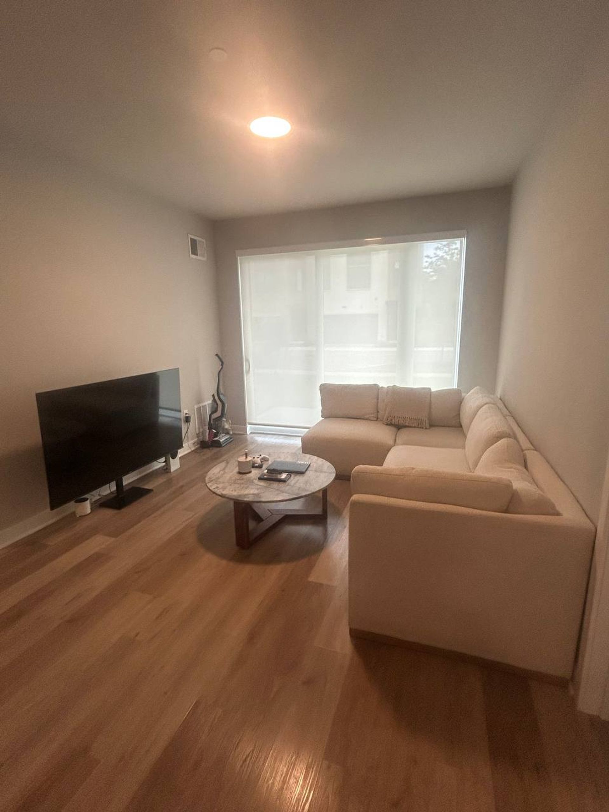 Living room with cream sectional, round coffee table and plank floor