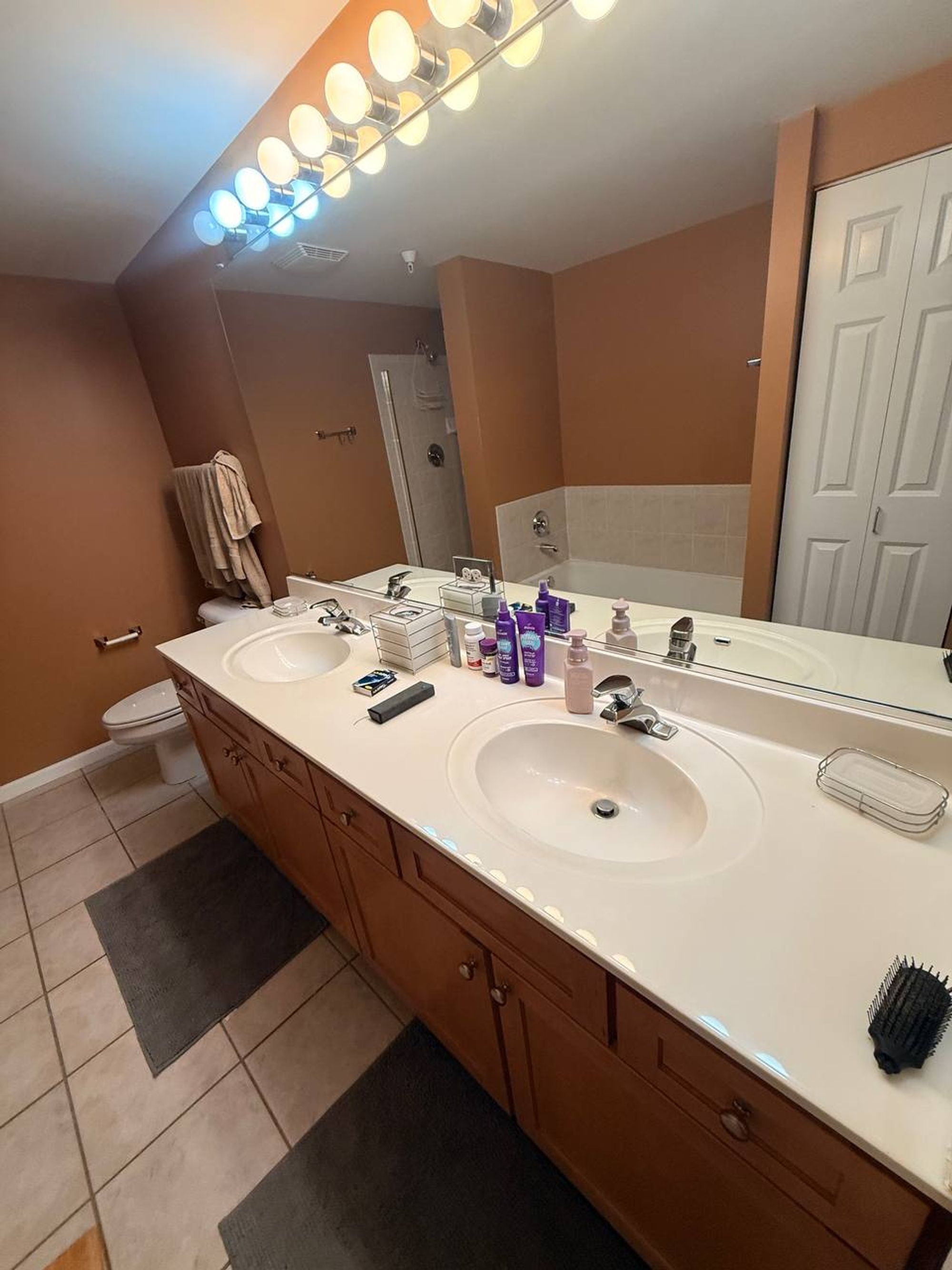 Long double vanity with two oval sinks and a wide mirror