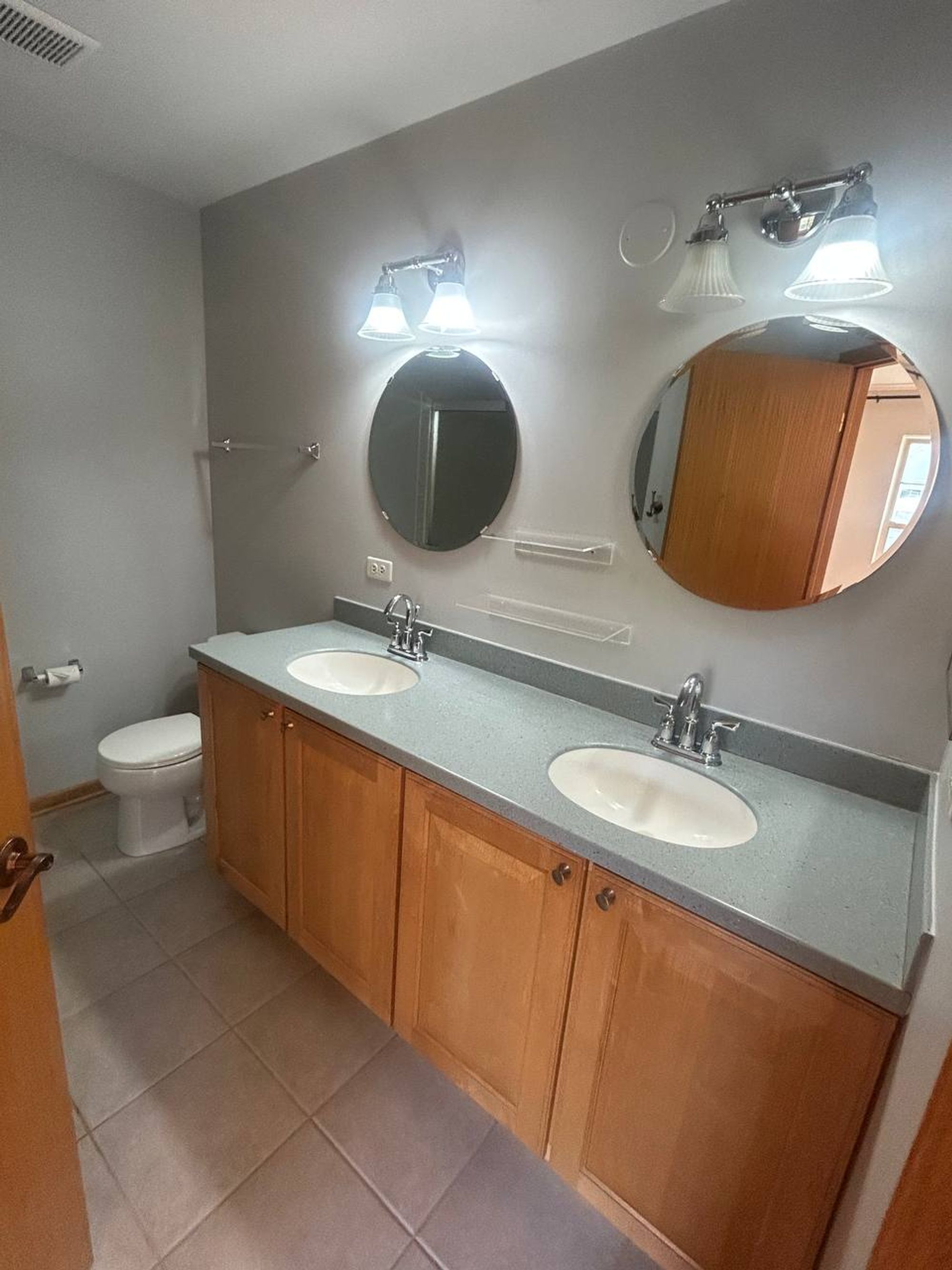 Empty bathroom with double sink vanity and two round mirrors