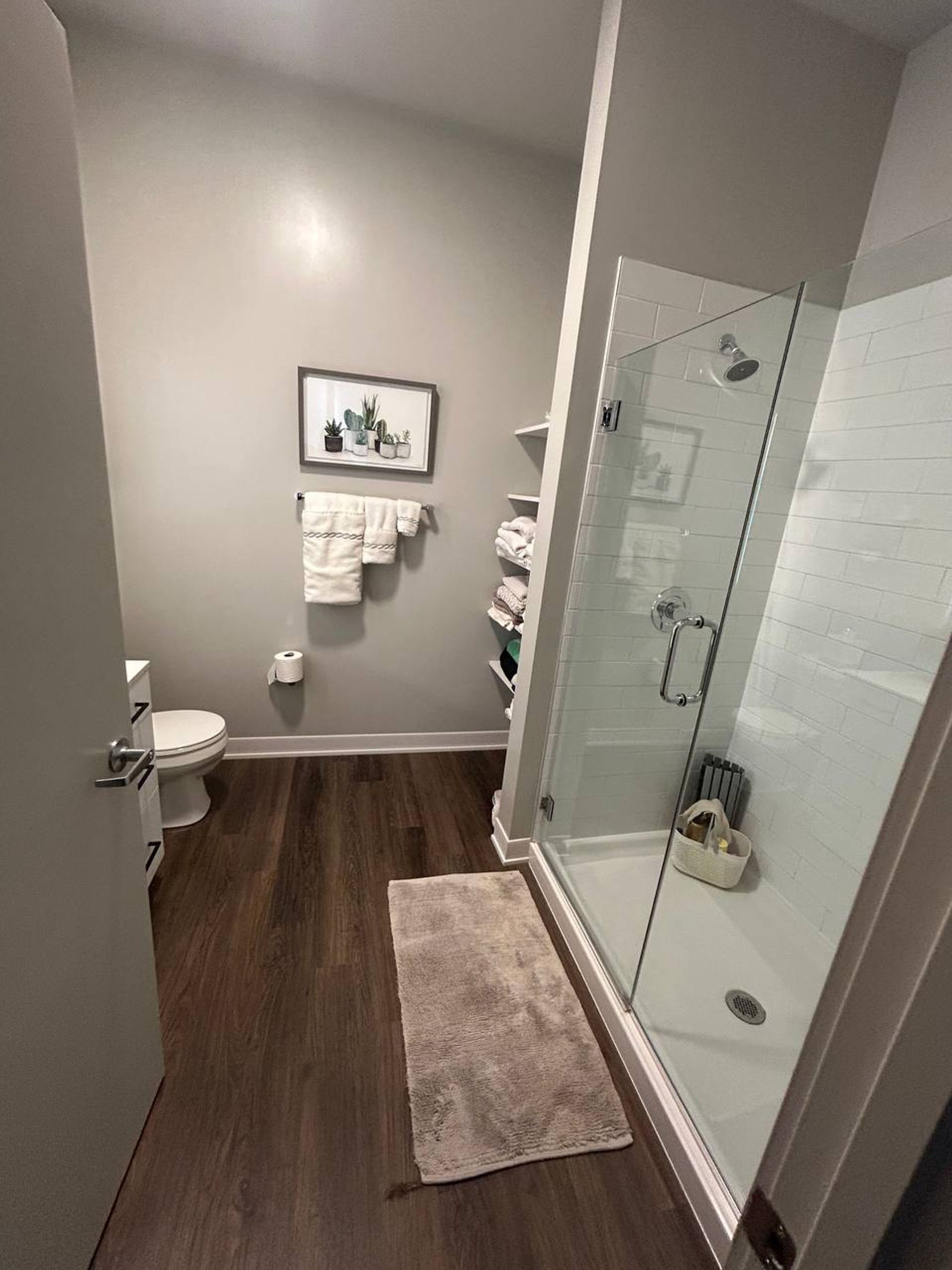 Bathroom with glass shower, white subway tile and dark plank floor