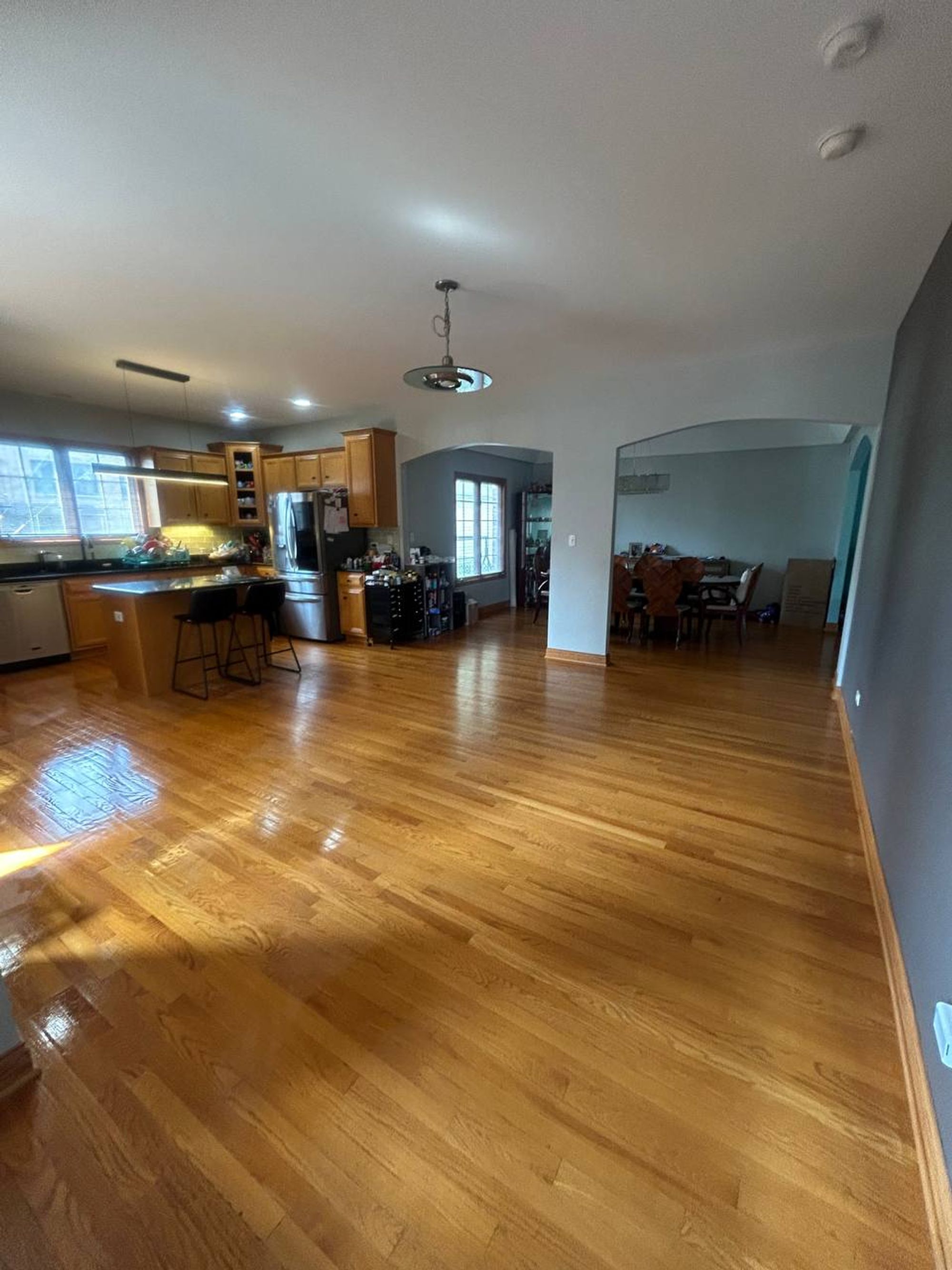 Open living space with hardwood floors leading to the kitchen and dining room