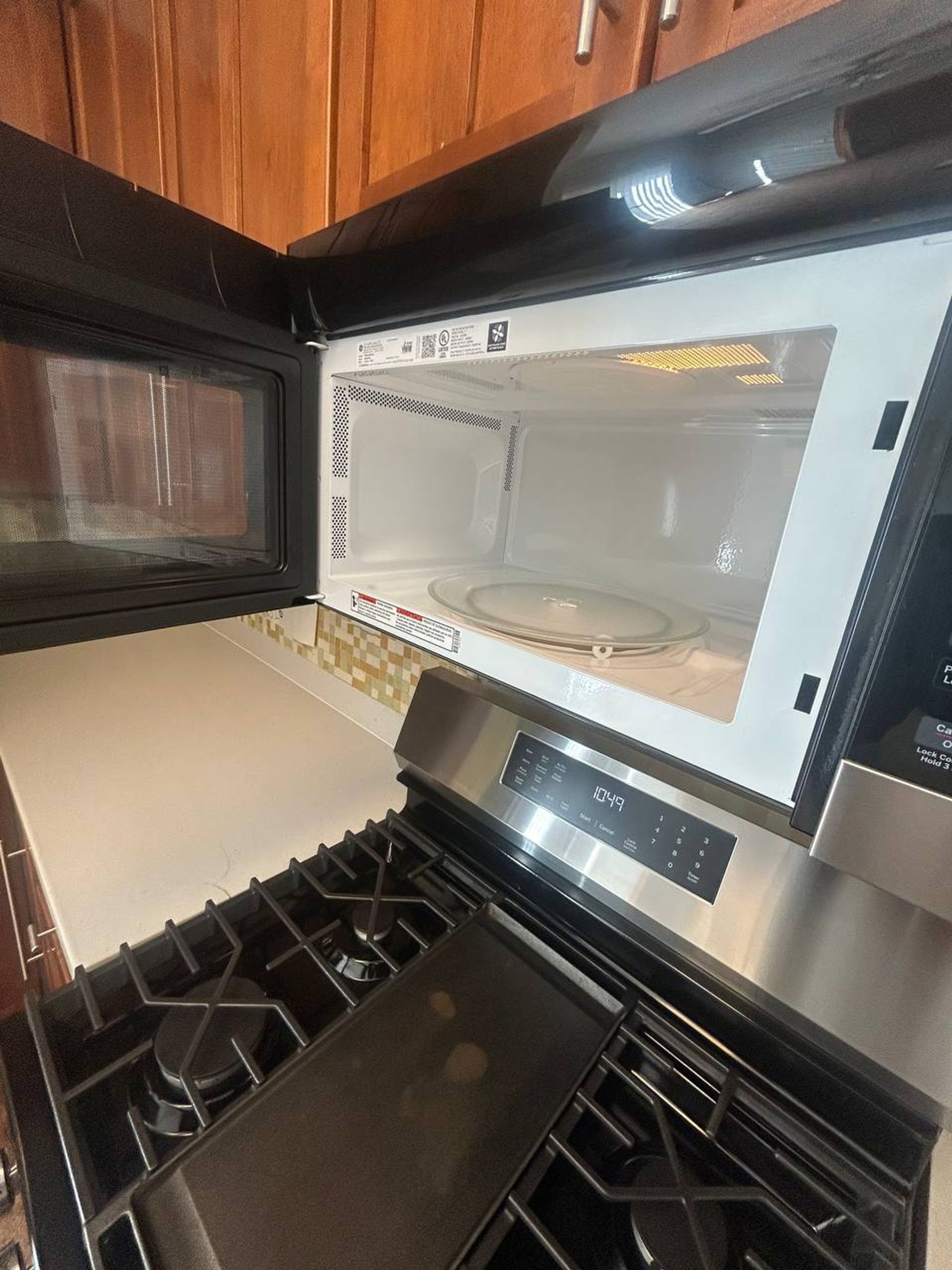 Open microwave above a gas range, both cleaned inside