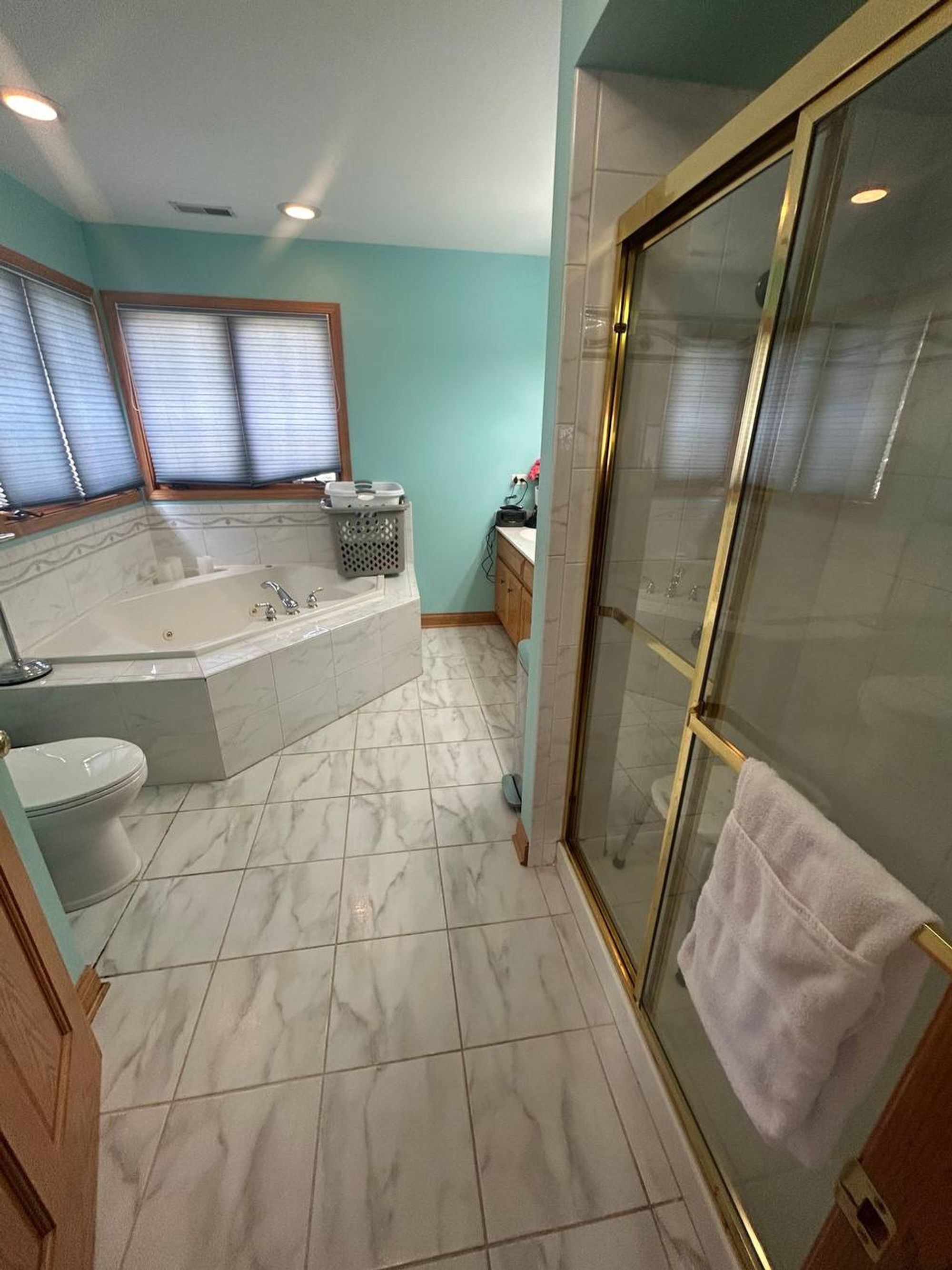 Main bathroom with corner tub, glass shower and marble look floor