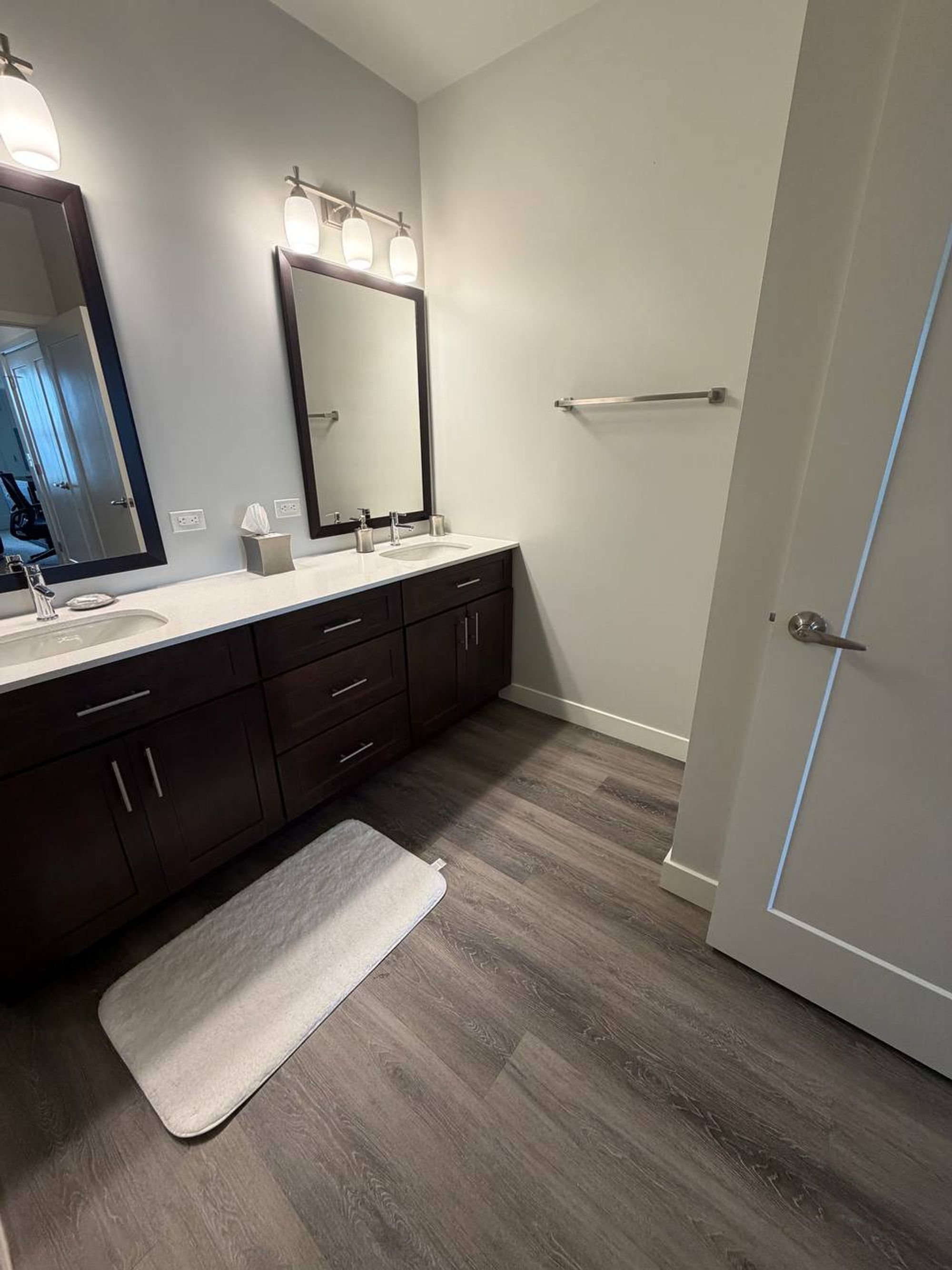 Bathroom with double sink vanity, white counters and a soft bath mat