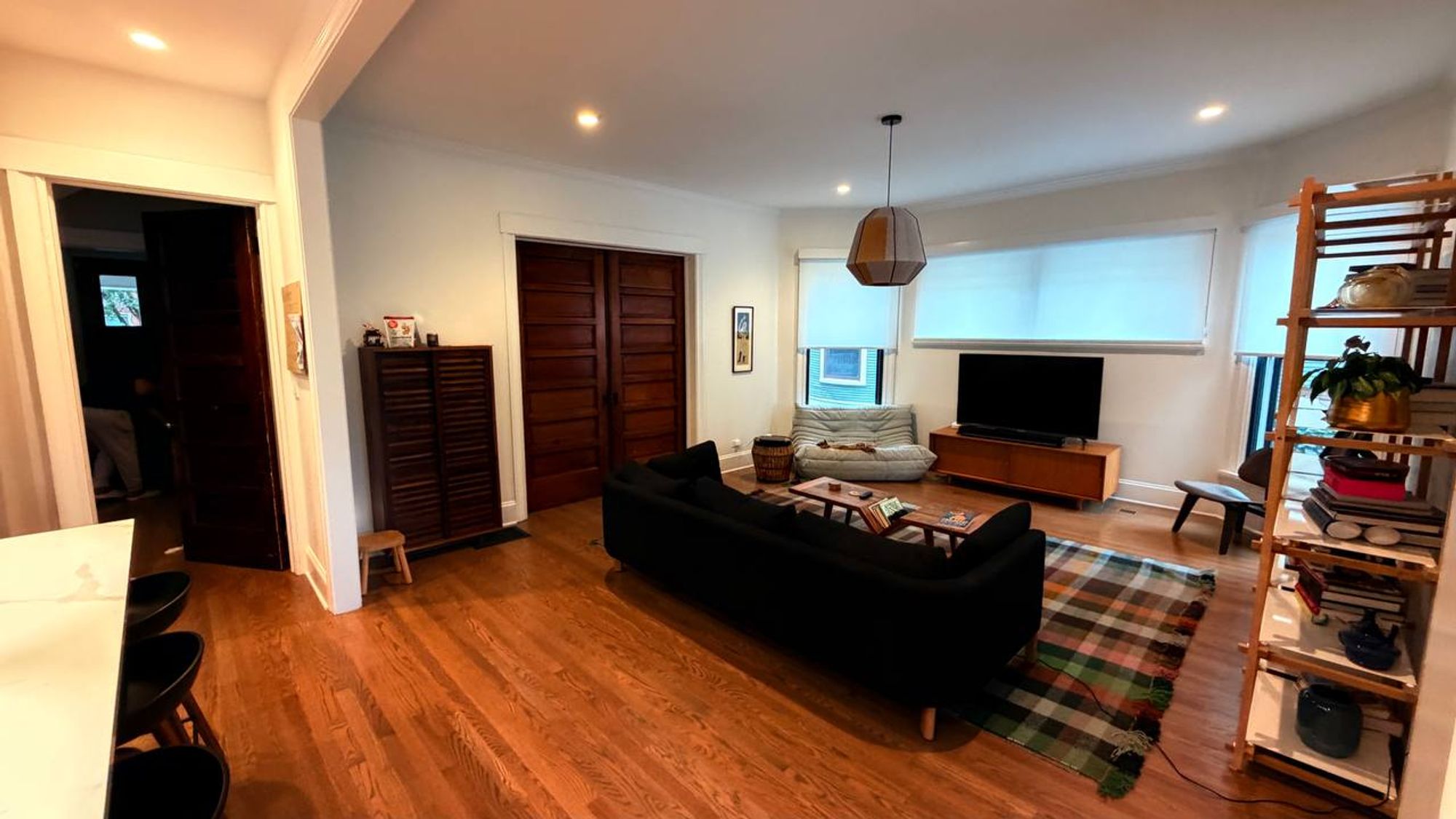 Living room with dark sofa, plaid rug and oak floors