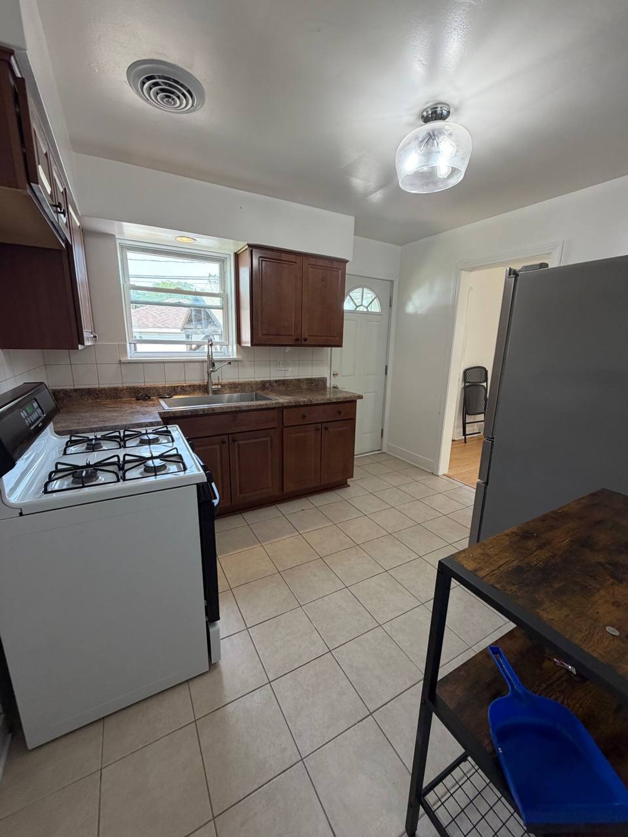 Empty kitchen with dark wood cabinets, gas range and tile floor