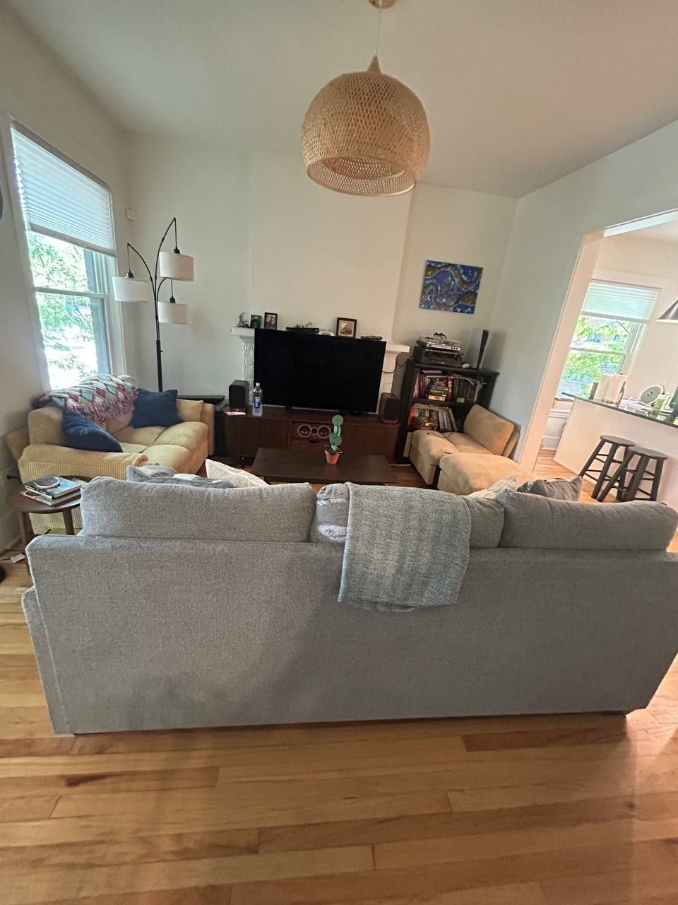 Living room with gray sectional, yellow chairs and oak floor