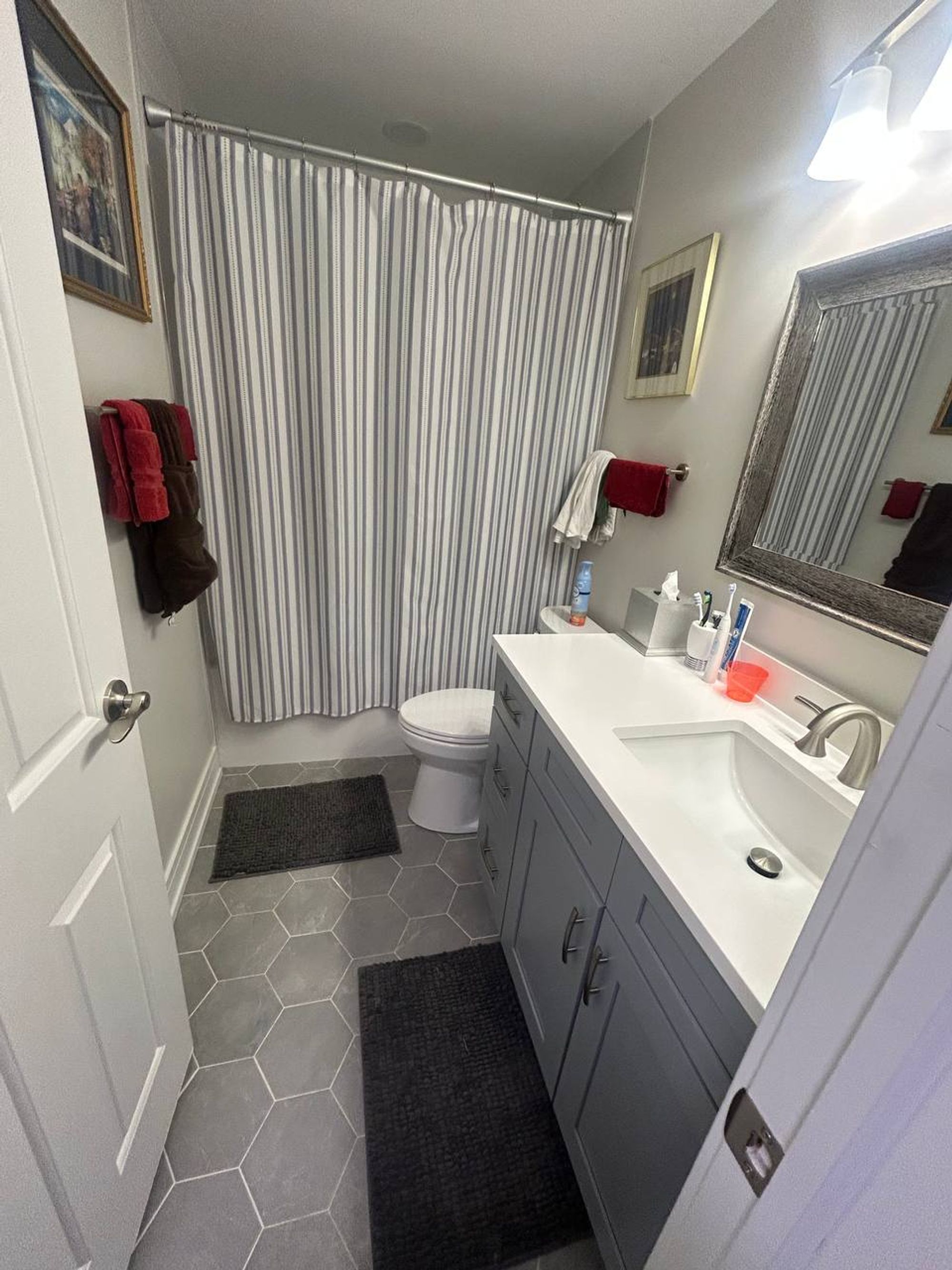 Hall bathroom with gray vanity, white top and gray hex tile floor
