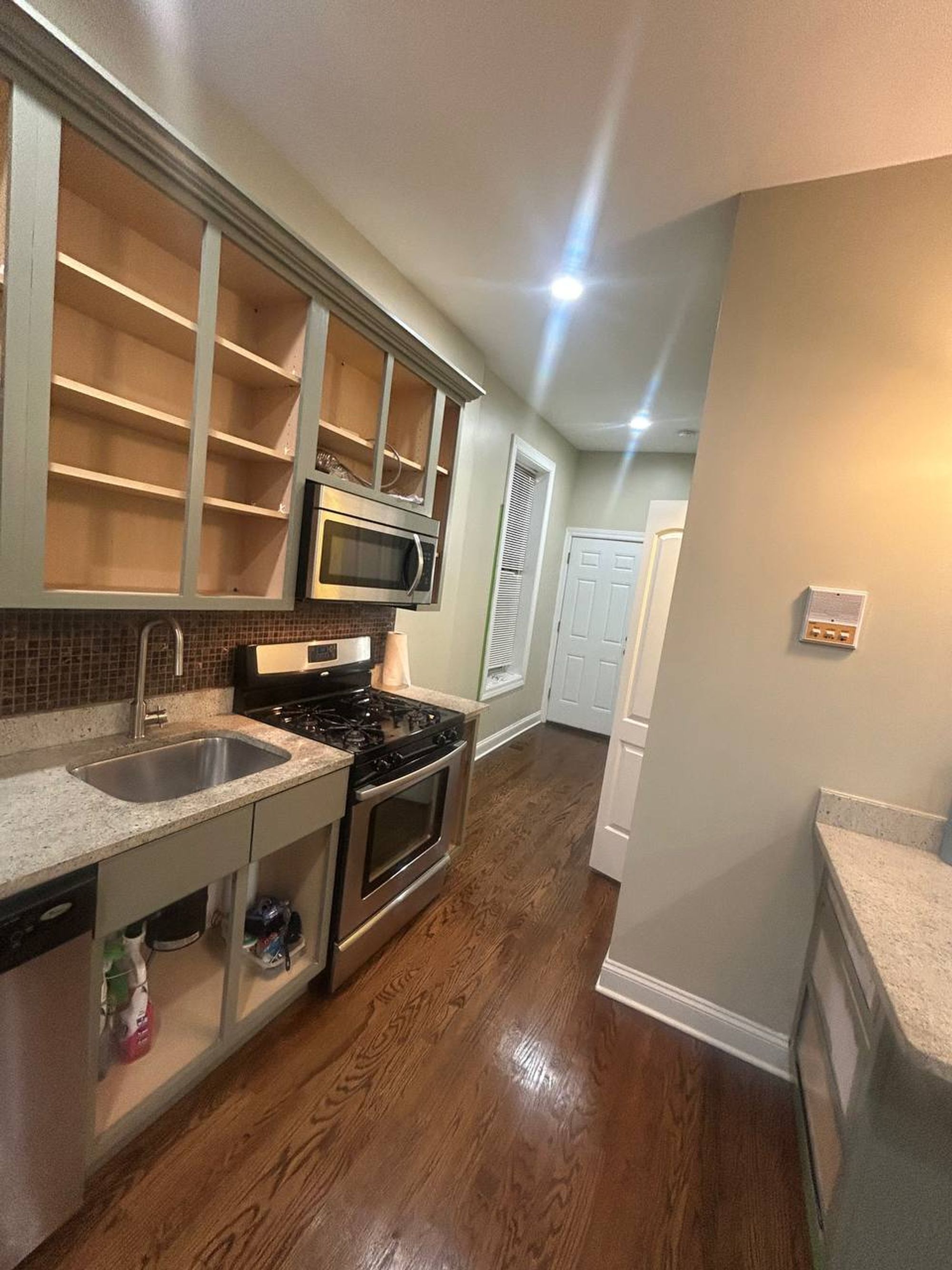 Kitchen with open cabinet shelves, granite counter and gas range