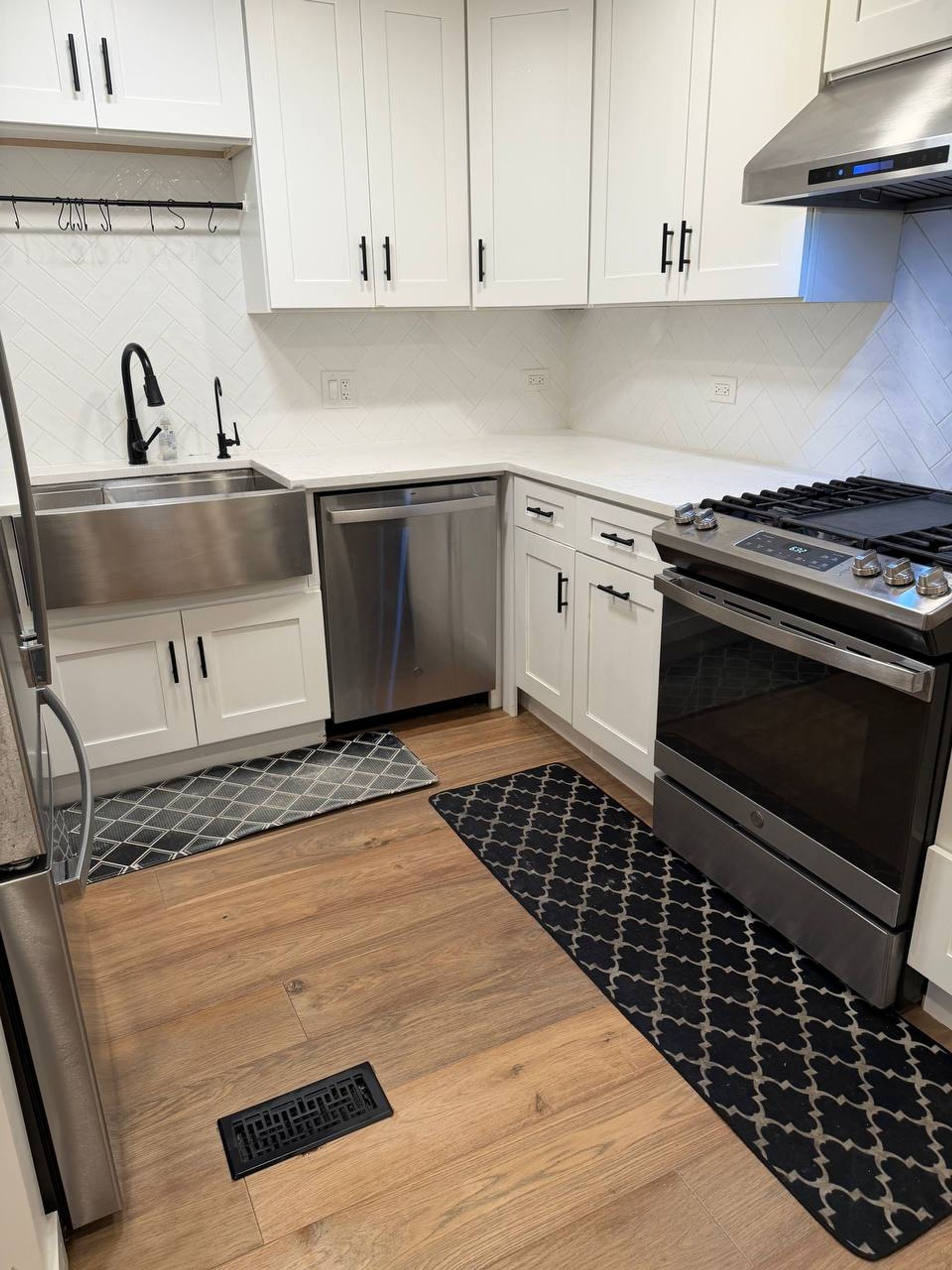 White kitchen corner with farmhouse sink, dishwasher and gas range