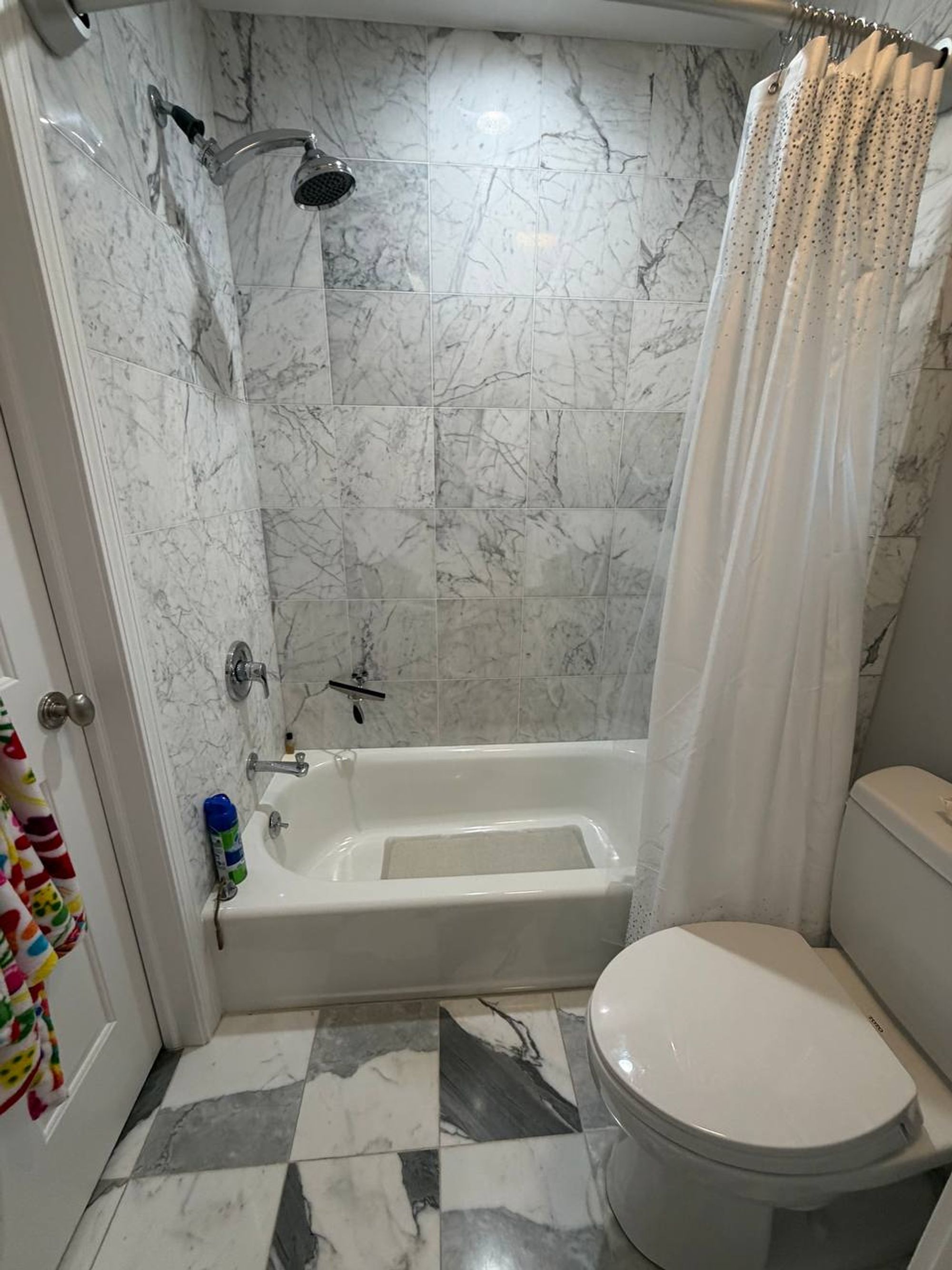 Marble tub surround and checkered marble floor in a bright bathroom