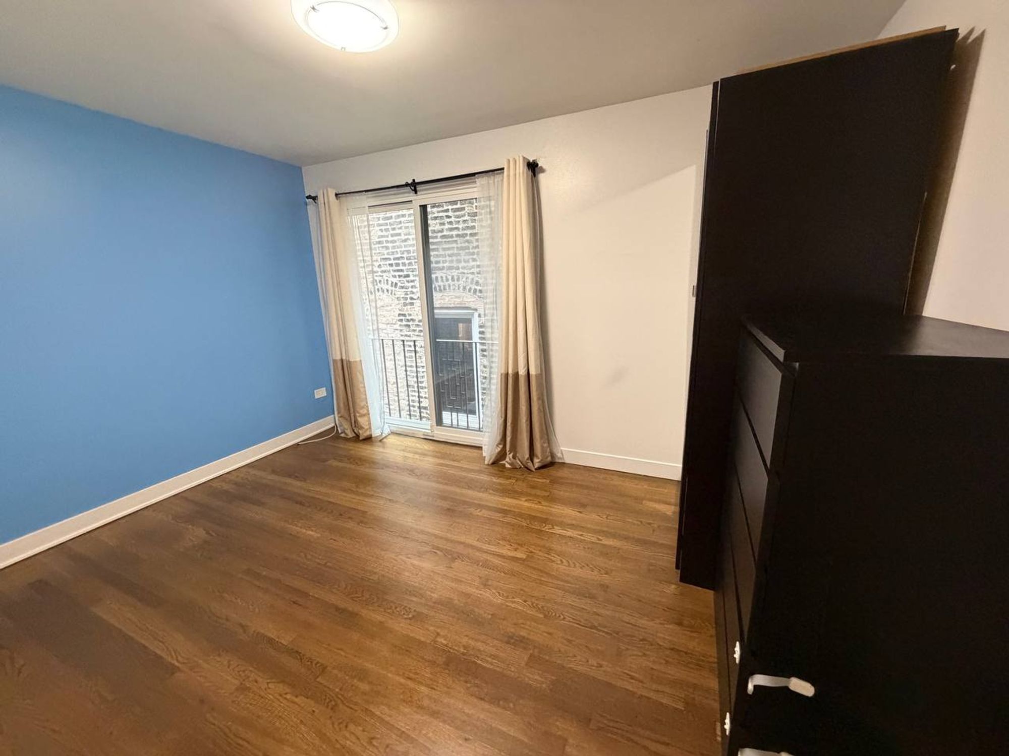 Bedroom with blue wall, clean oak floor and balcony door