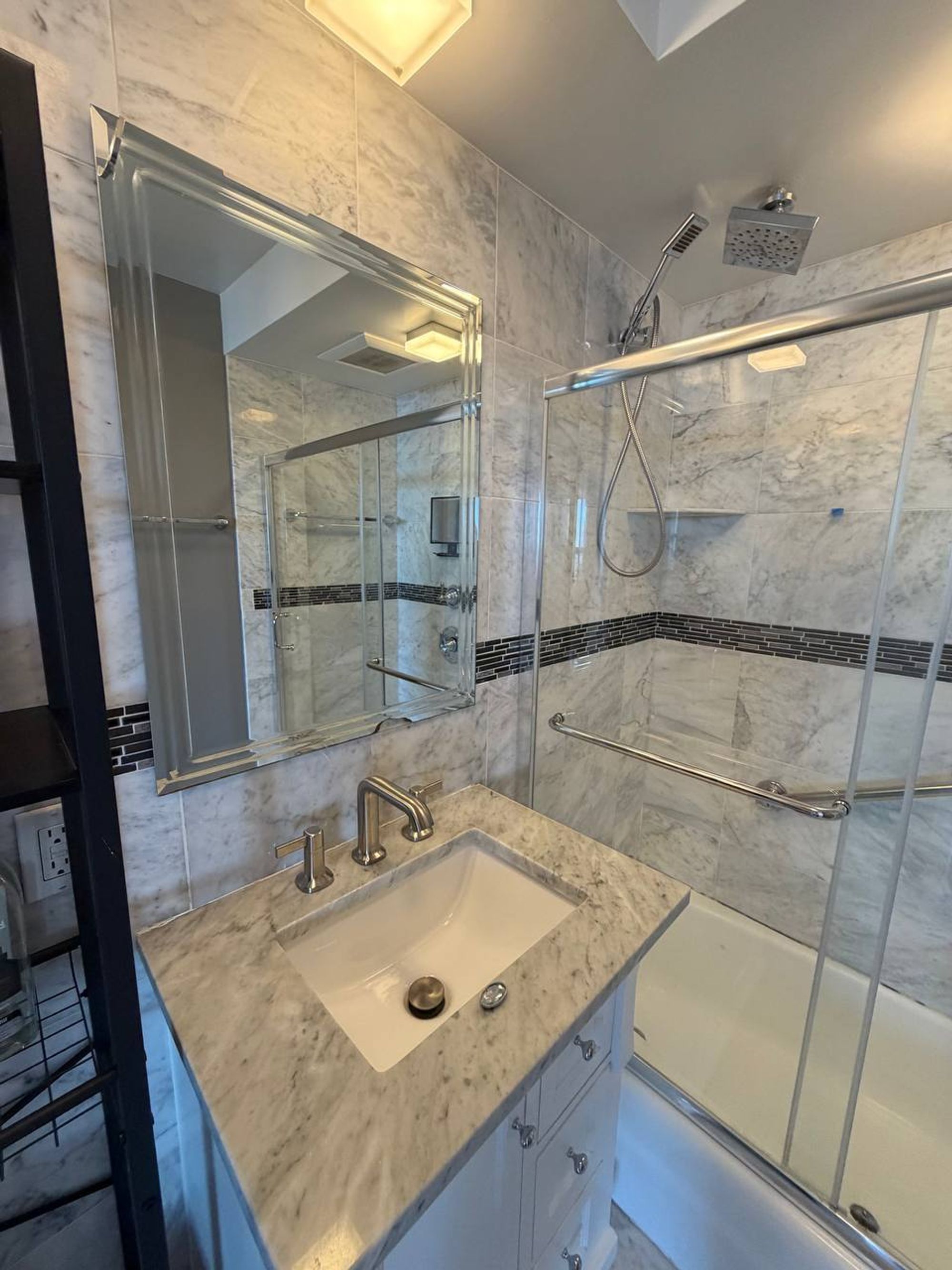 Marble vanity with undermount sink, framed mirror and glass shower