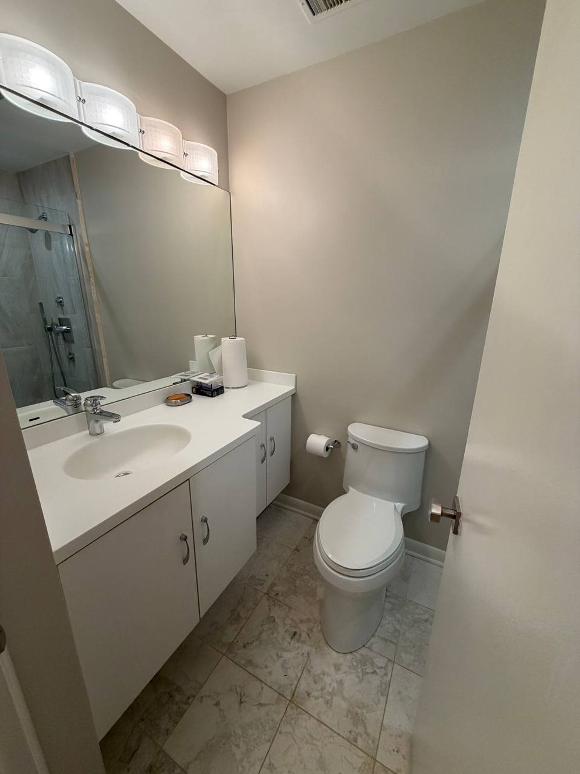 Bathroom with white floating vanity, wall mirror and marble look tile