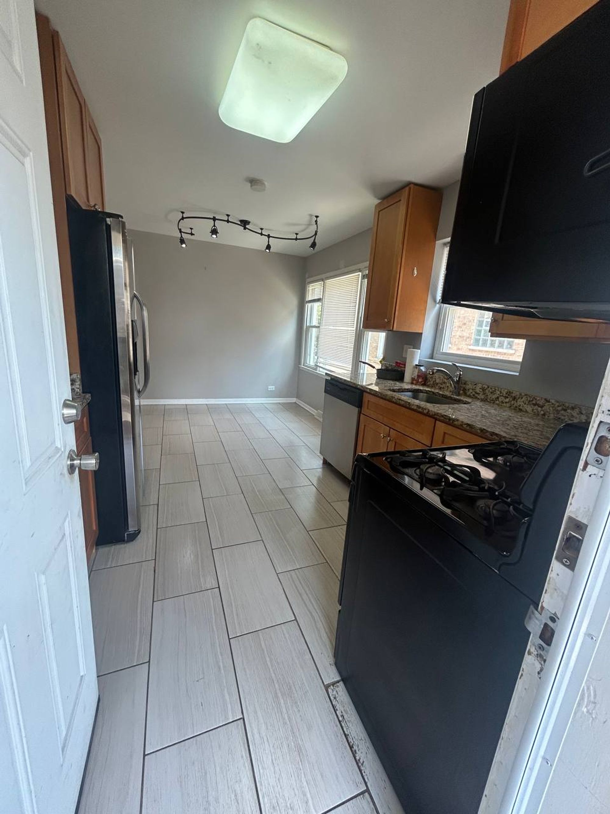 Galley kitchen with tile floor, gas range and stainless fridge