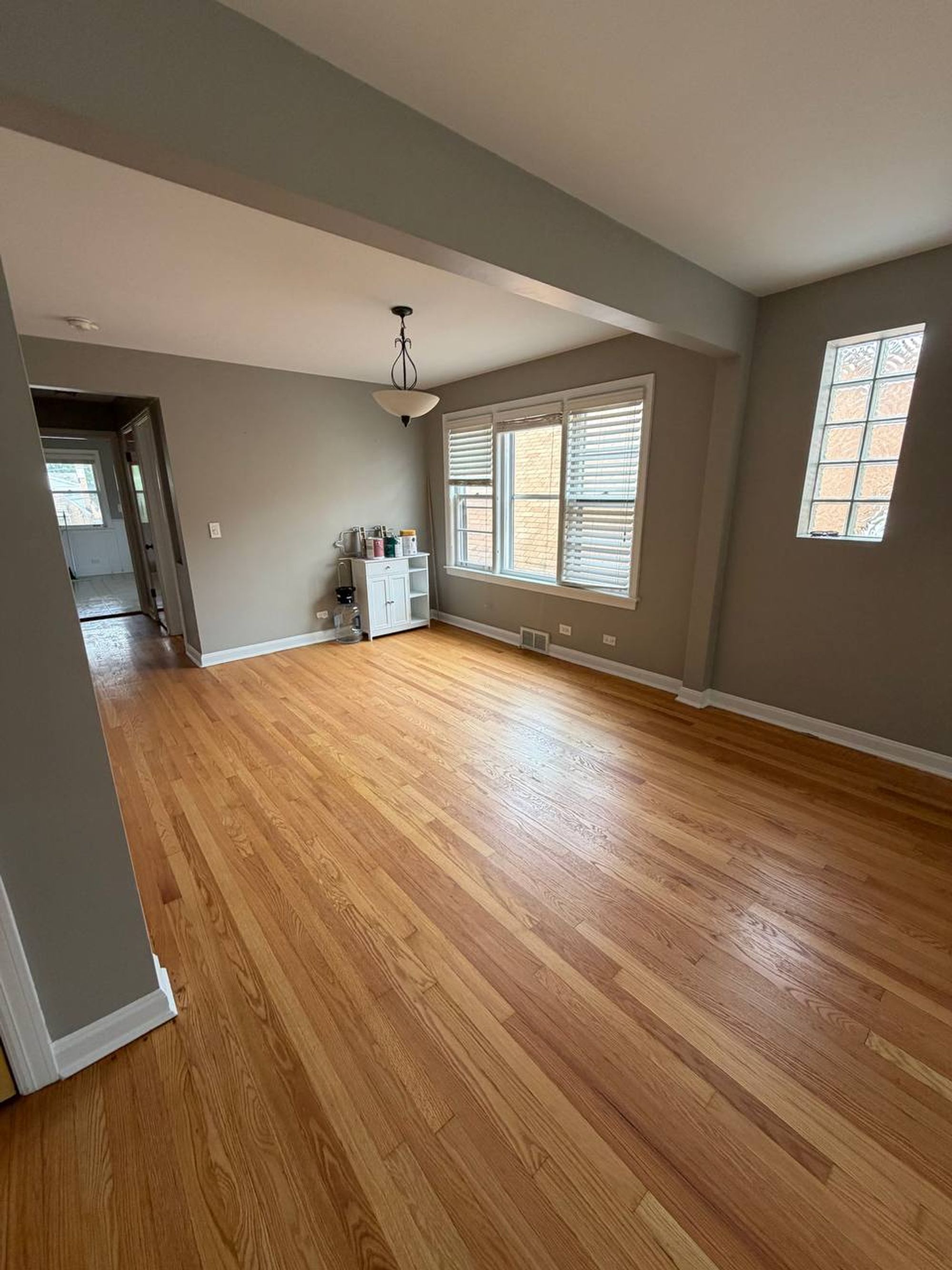Empty dining room with pendant light, windows and oak floor