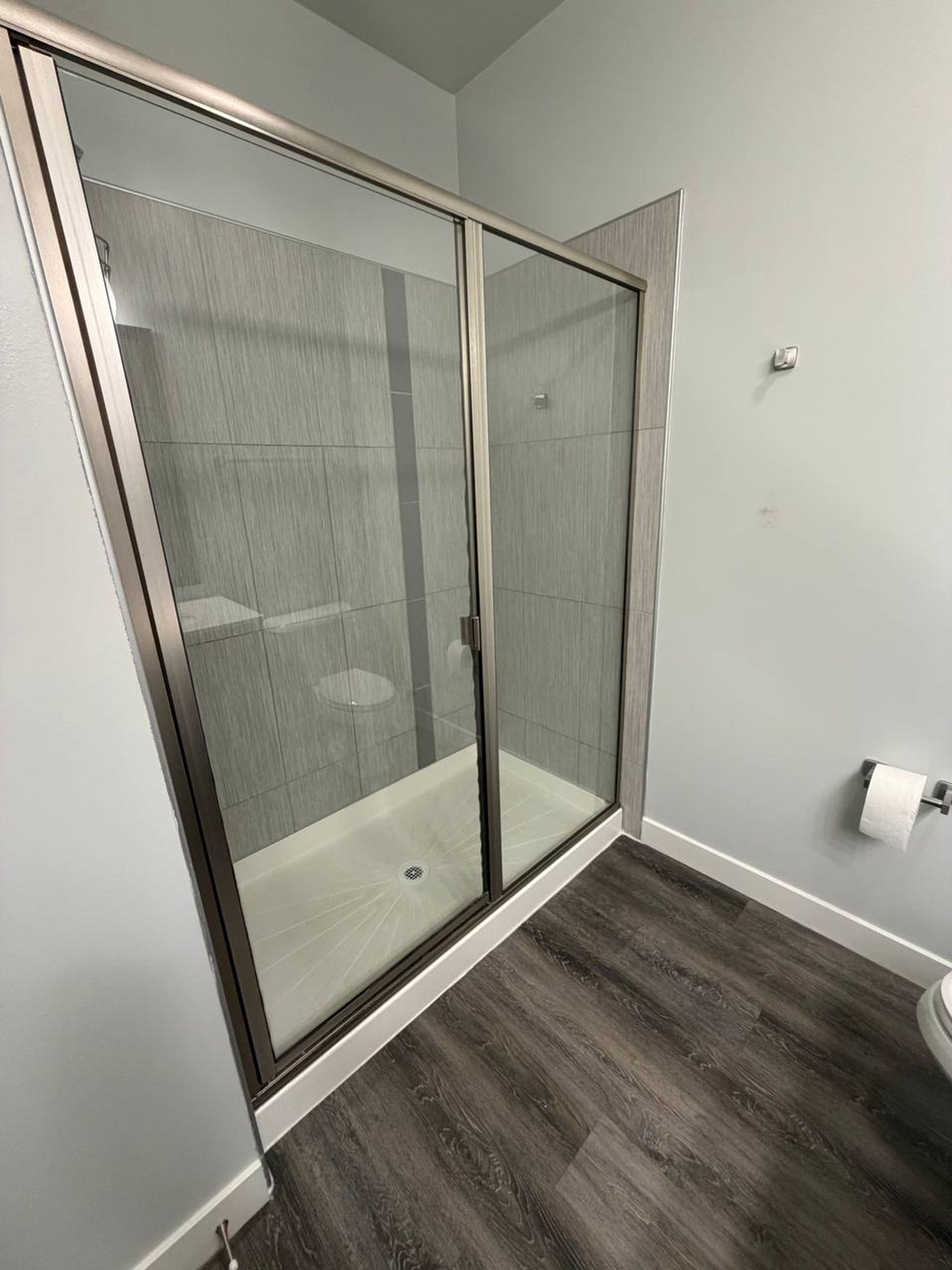 Walk-in shower with framed glass door and gray tile walls