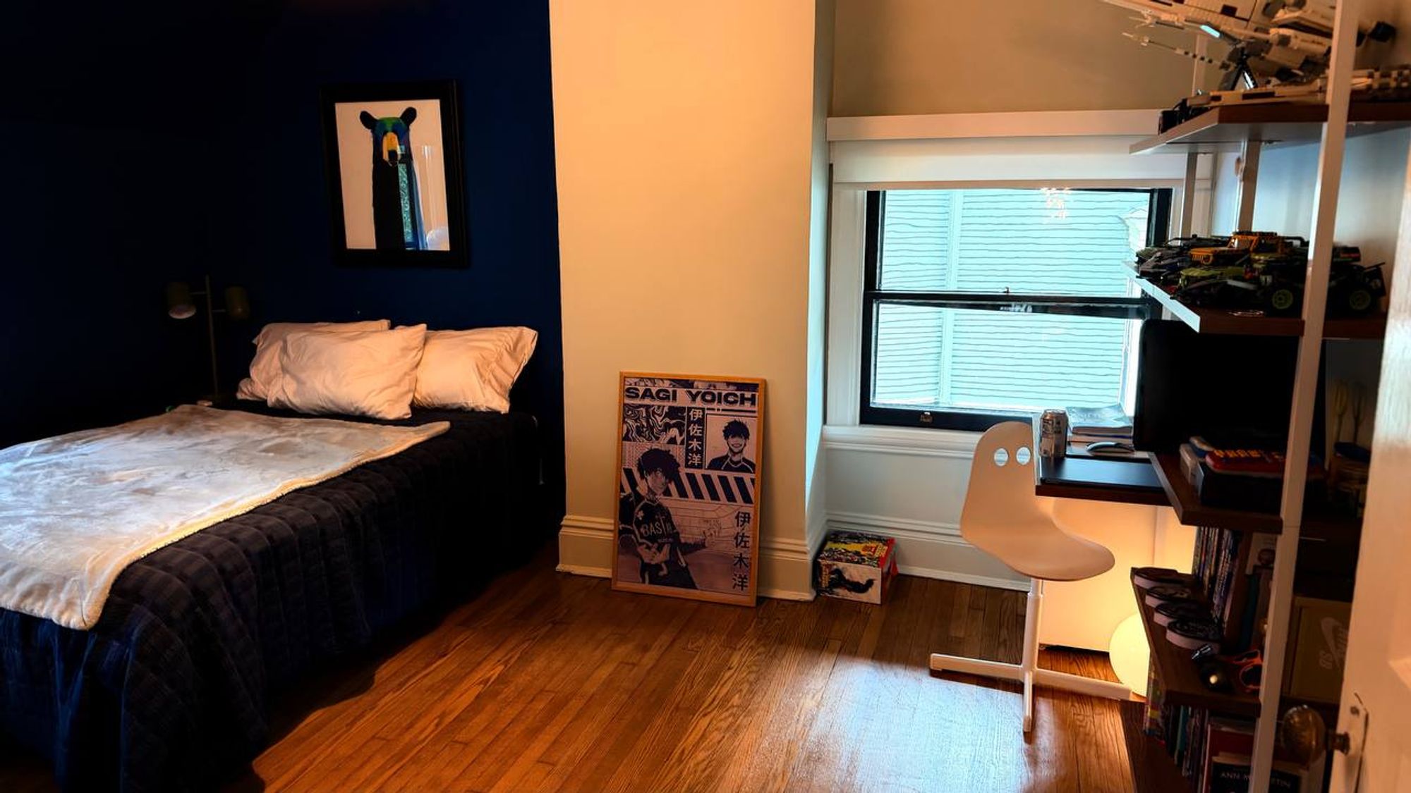Bedroom with navy accent wall, made bed and wood floor